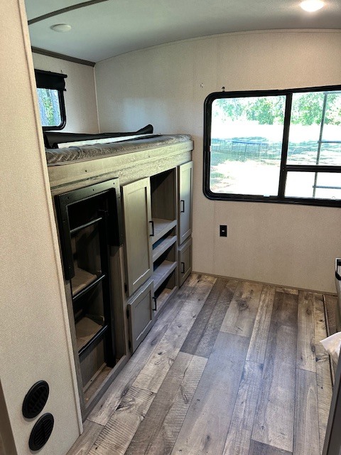 Spacious RV rental bunk room features a comfortable bed, versatile storage cabinets, and a large window.. Keystone RV Outback 2020