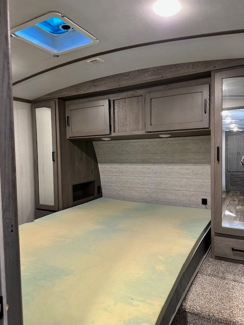 RV rental bedroom: a compact camper interior with a foam mattress, overhead cabinets, and mirrored wardrobes.. Keystone RV Outback 2020