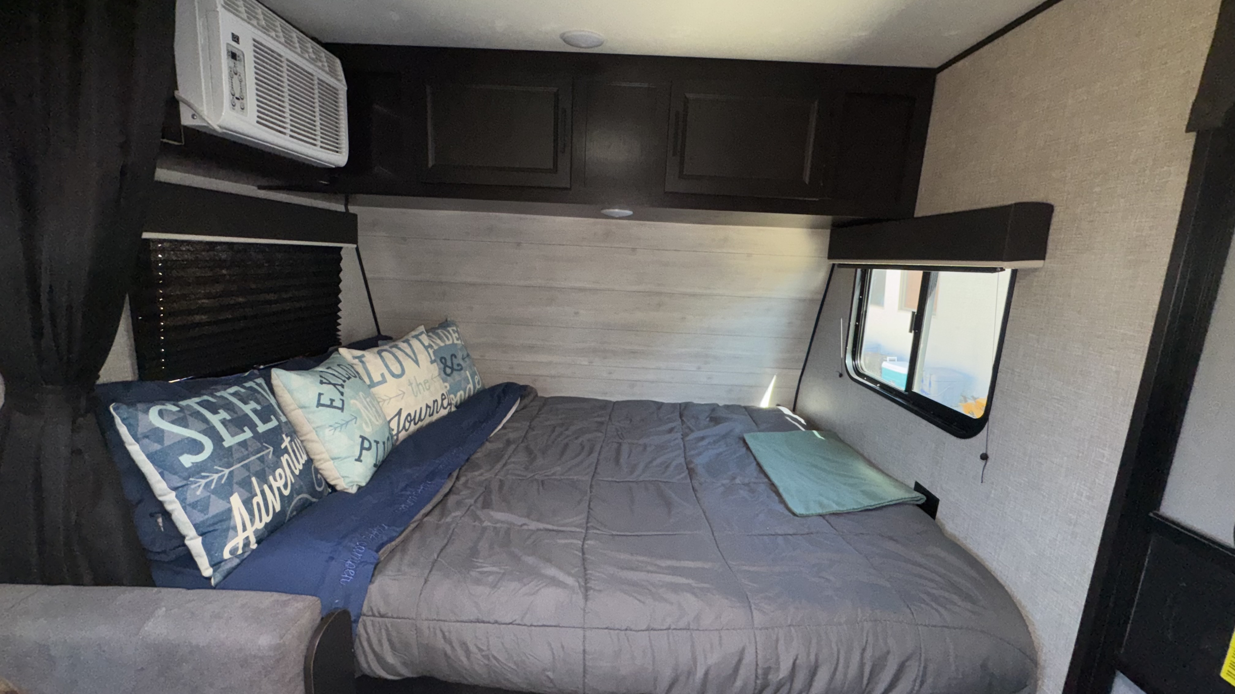 Cozy RV rental bedroom: queen bed with decorative pillows, overhead storage, window AC, and blackout blinds.. Jayco Jay Flight SLX 2022