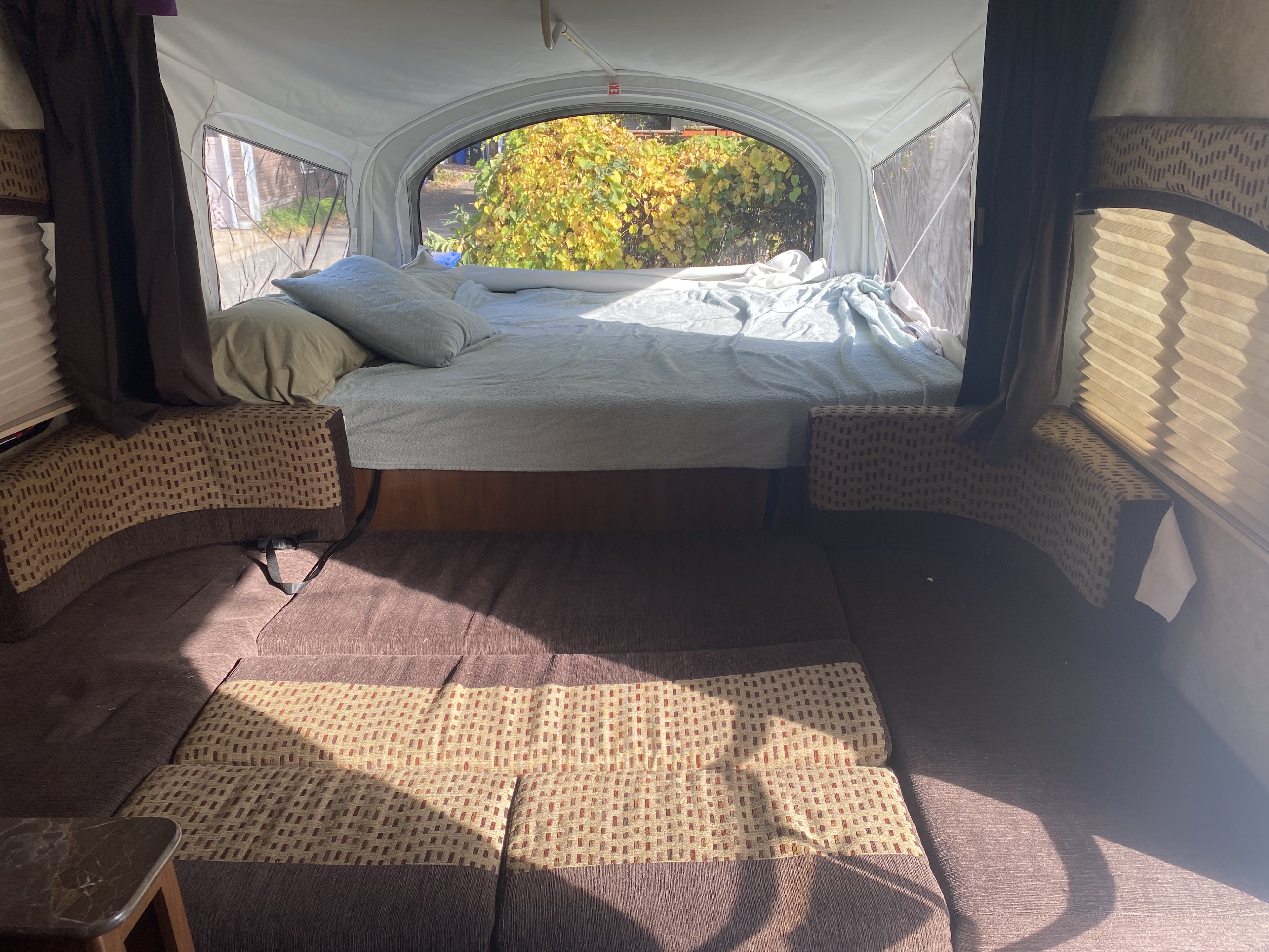 Cozy RV rental interior with a comfortable bed, seating area, and large window showcasing vibrant autumn foliage.. Jayco Jay Feather 7 2016
