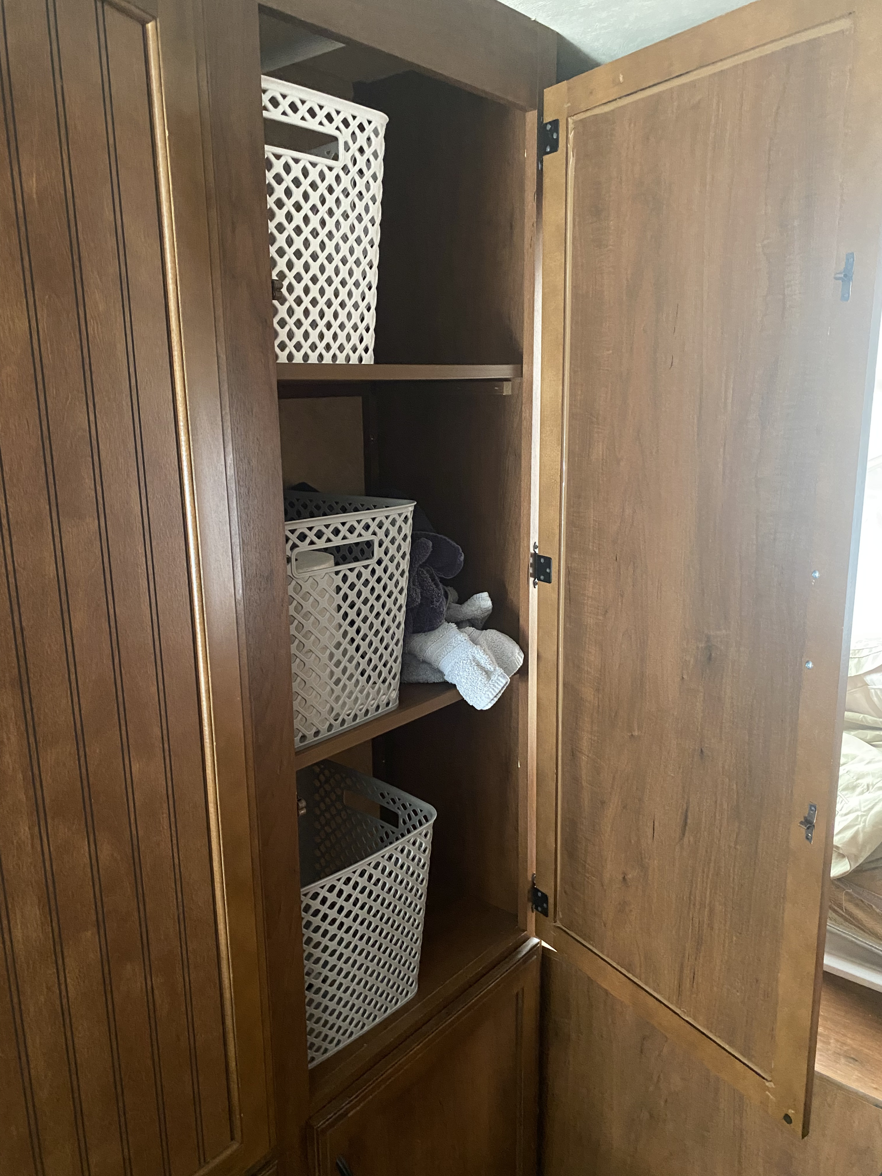 Open wooden cabinet inside an RV rental, featuring shelves with white storage baskets and plush items. Efficient storage for travel.. Jayco Jay Feather 7 2016