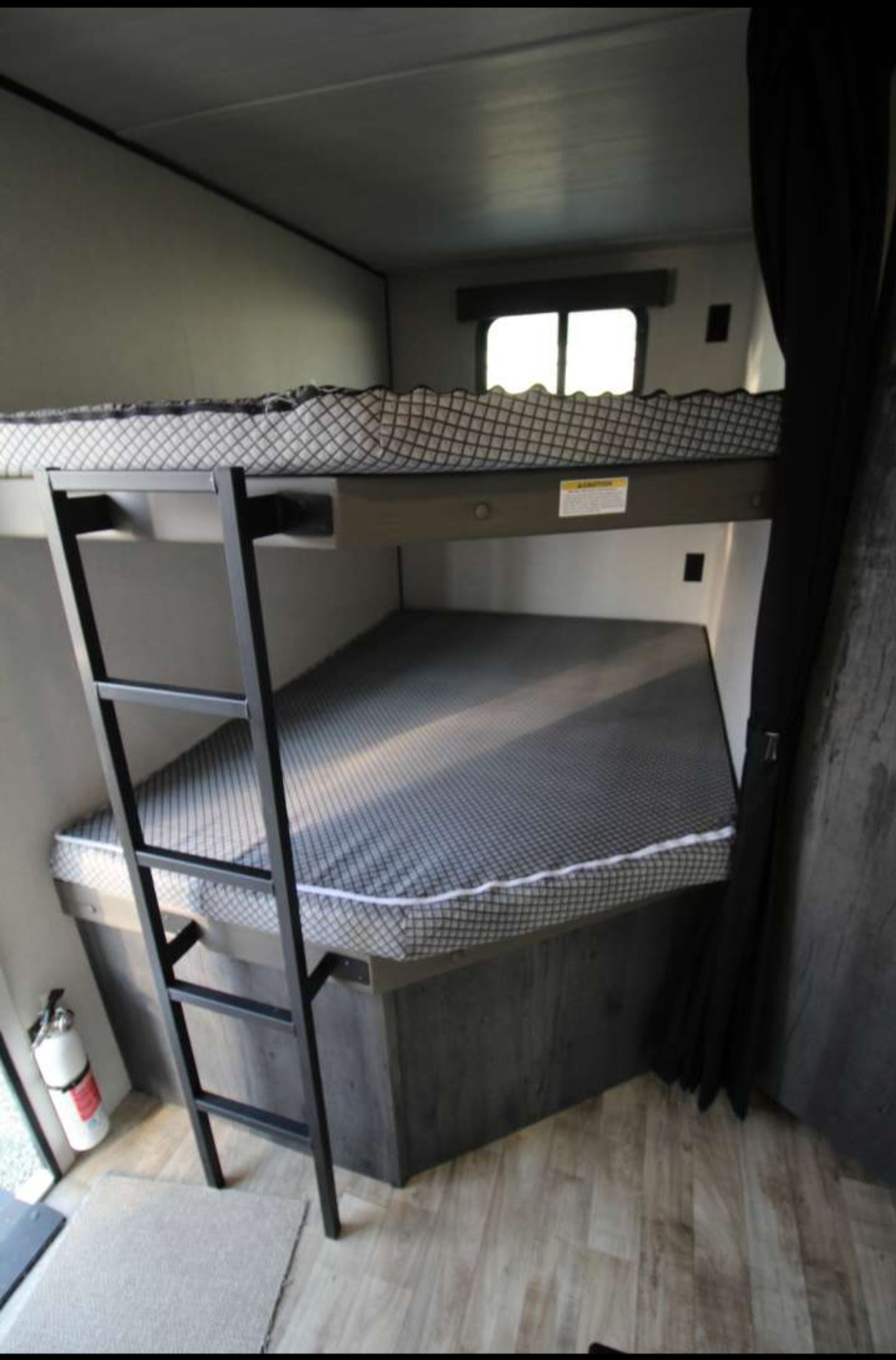 View of an RV rental bunk bed area: upper bed has a safety net & a ladder. Lower bed below a window.. Keystone RV Hideout 2022