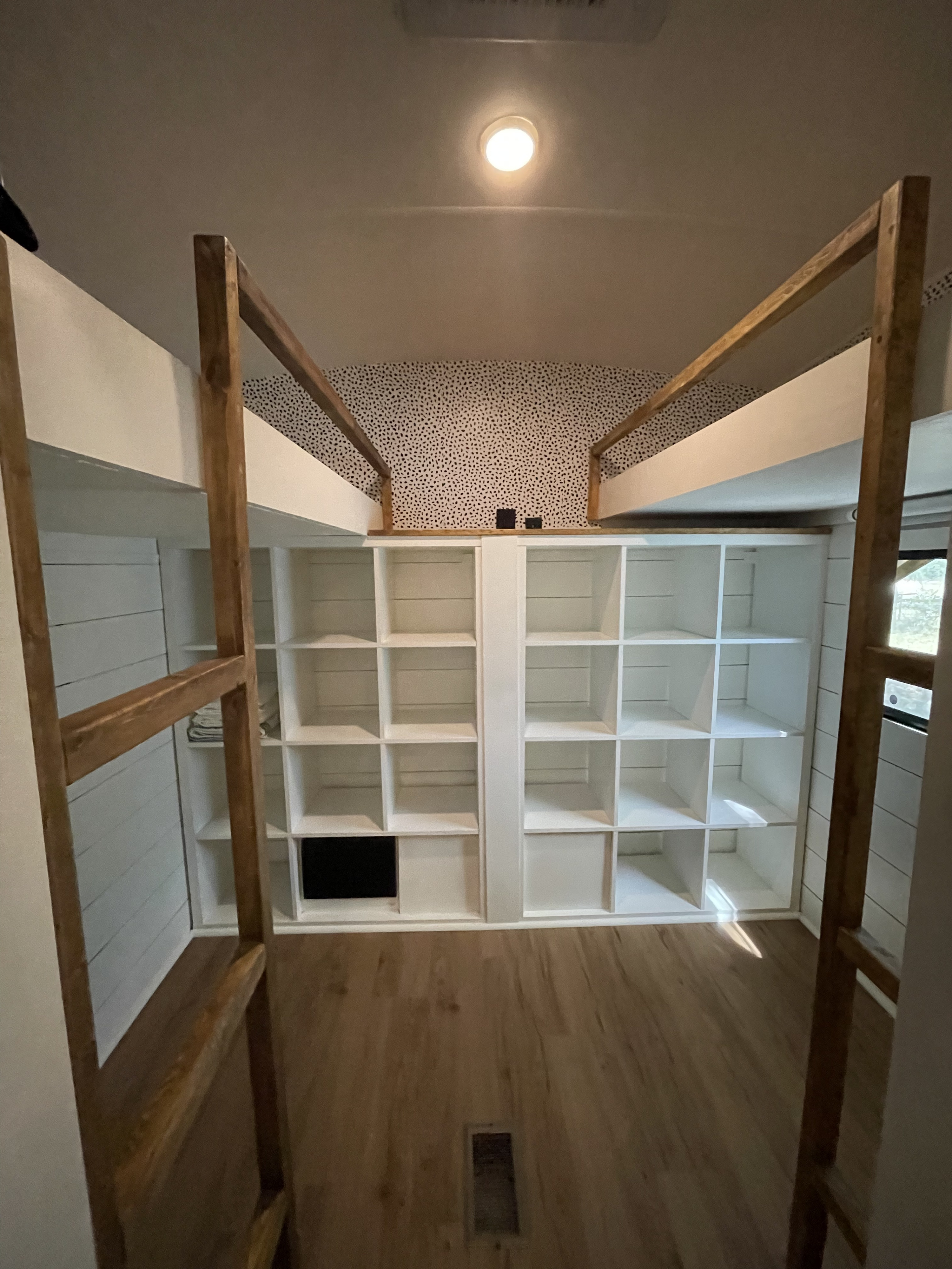 This RV rental features a bright interior with wooden bunk beds, extensive built-in cubby shelving, and stylish polka dot wallpaper.. Forest River Wildcat Extralite 2013