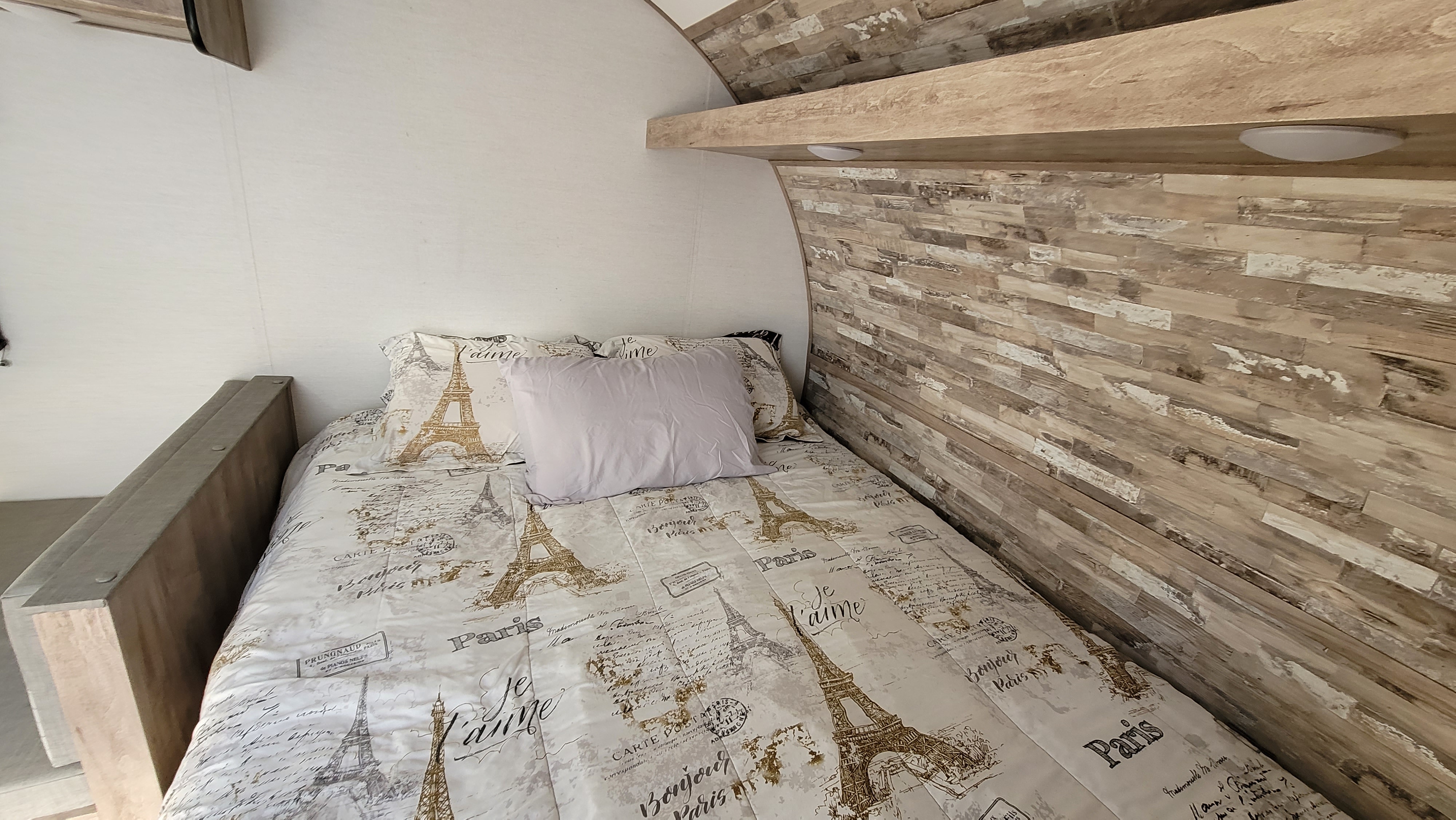 RV rental: Cozy bedroom featuring Paris-themed bedding, a light wood paneled wall, and an overhead shelf.. Gulf Stream Ameri-Lite 2024