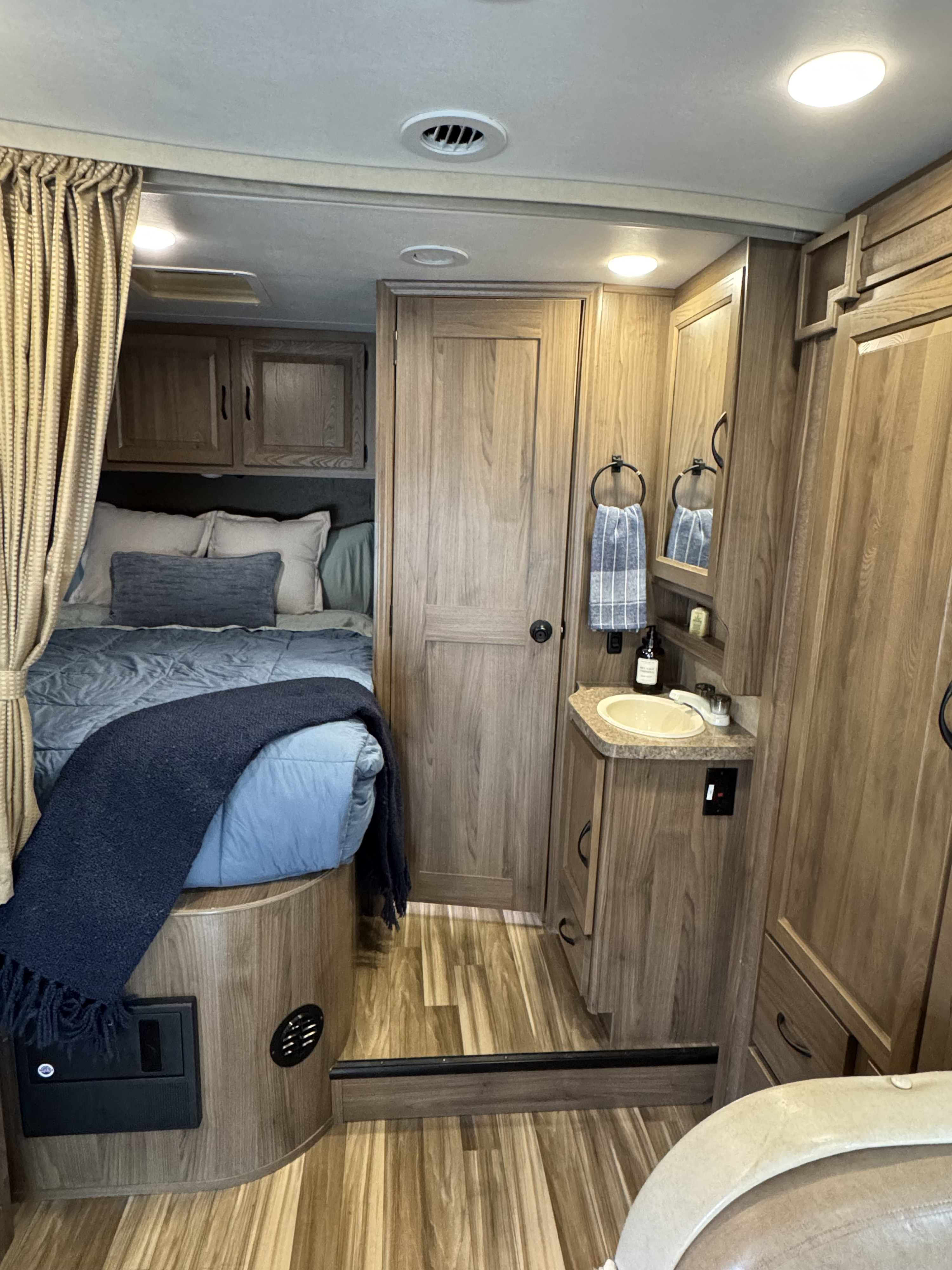 Inside an RV rental, discover a comfortable bed, functional bathroom sink, and ample wooden storage, creating a cozy living space.. Forest River Coachmen Prism 2017