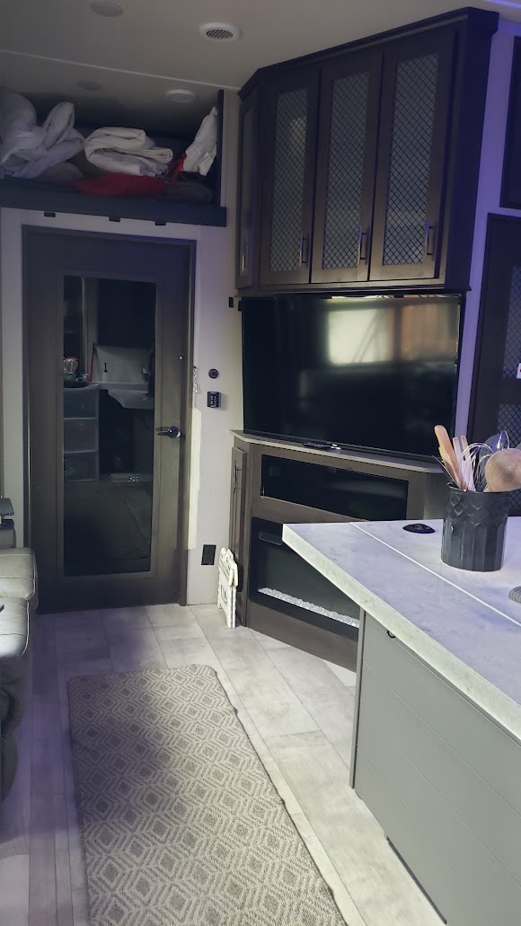 Modern RV rental interior: living space with TV, fireplace, kitchen island, and bunk bed area, designed for comfort.. Grand Design Momentum Toy Hauler 2021
