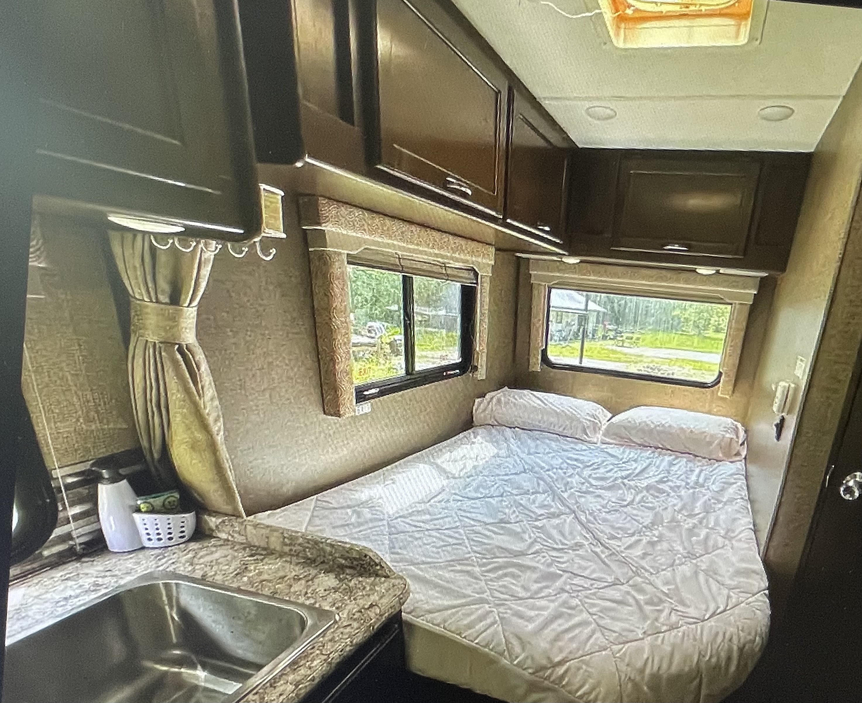 Experience comfort in this RV rental: a cozy bed, kitchen sink, and natural light from large windows.. Thor Freedom Elite 2018