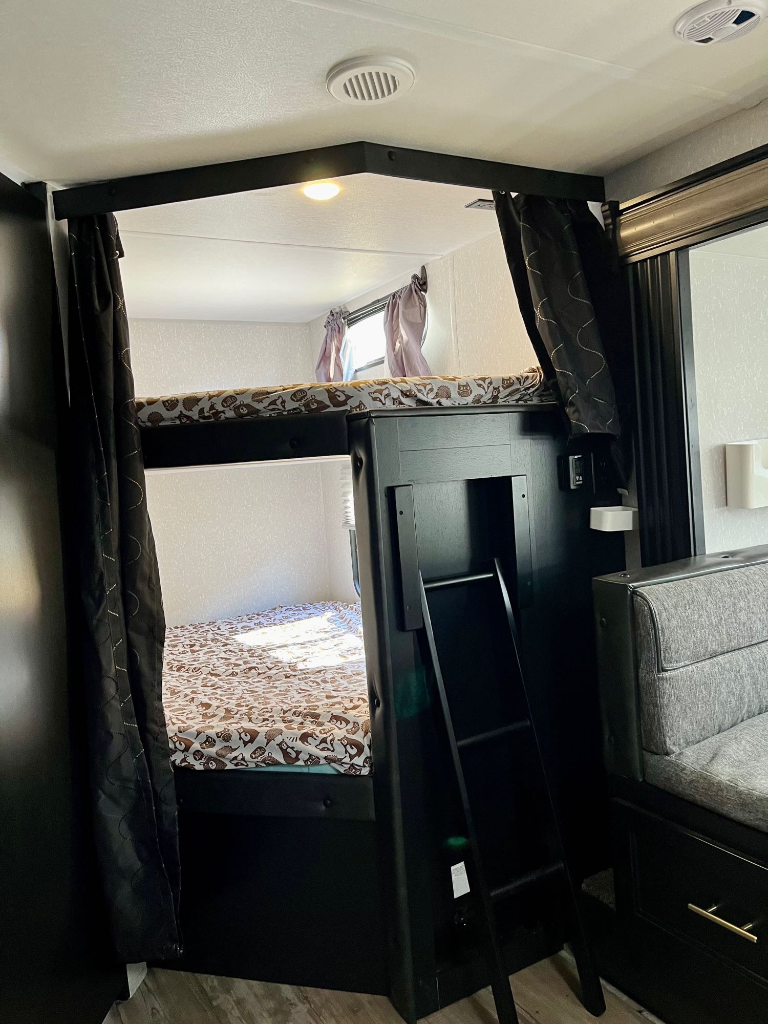 Cozy RV rental bunk beds with fun patterned sheets, privacy curtains, and a ladder for easy access.. Forest River Cherokee Grey Wolf 2021