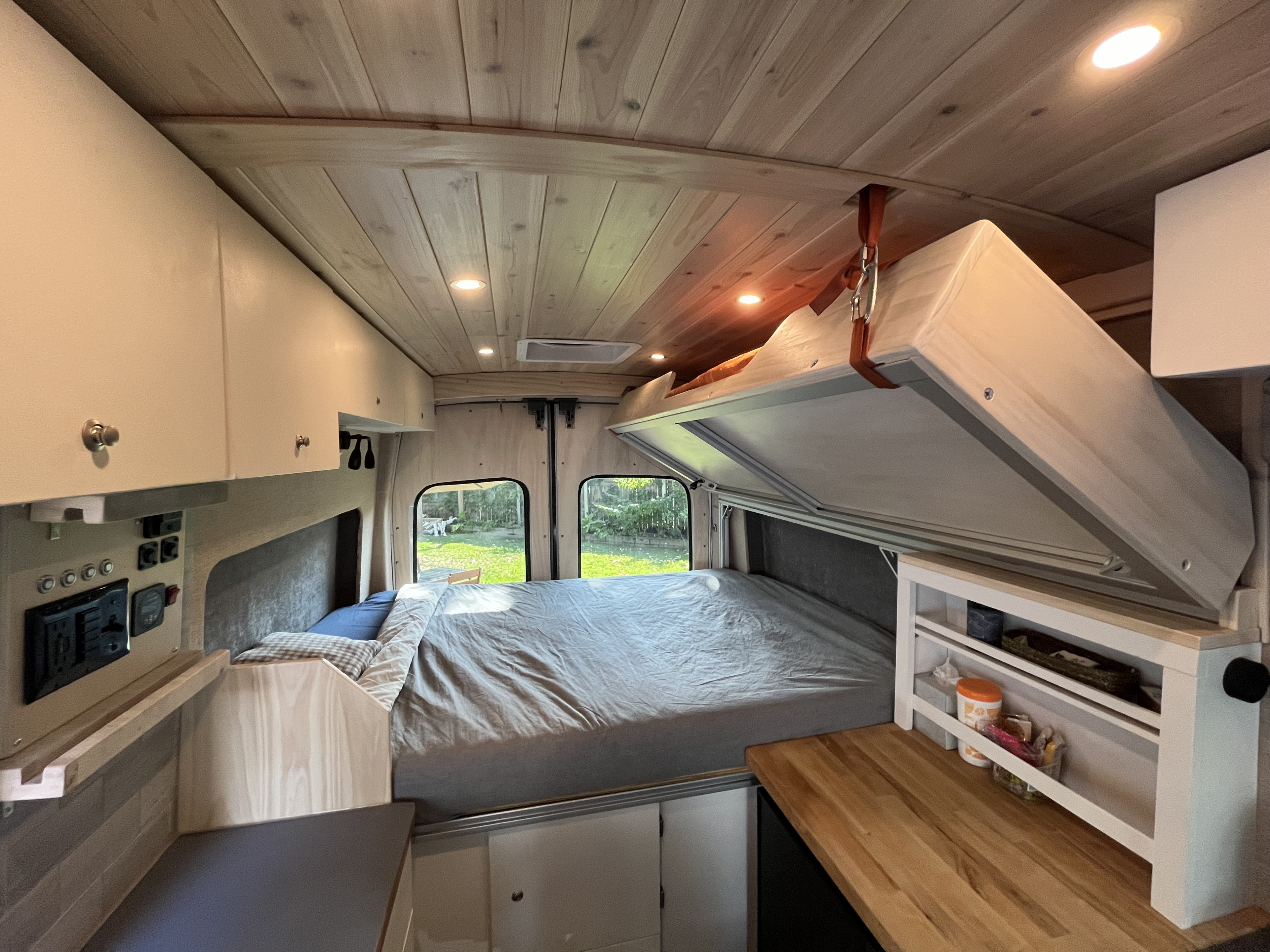 RV rental: Cozy camper van interior with lift bed, wooden ceiling, and kitchen counter for comfortable travel.. Custom Built Transit 2017
