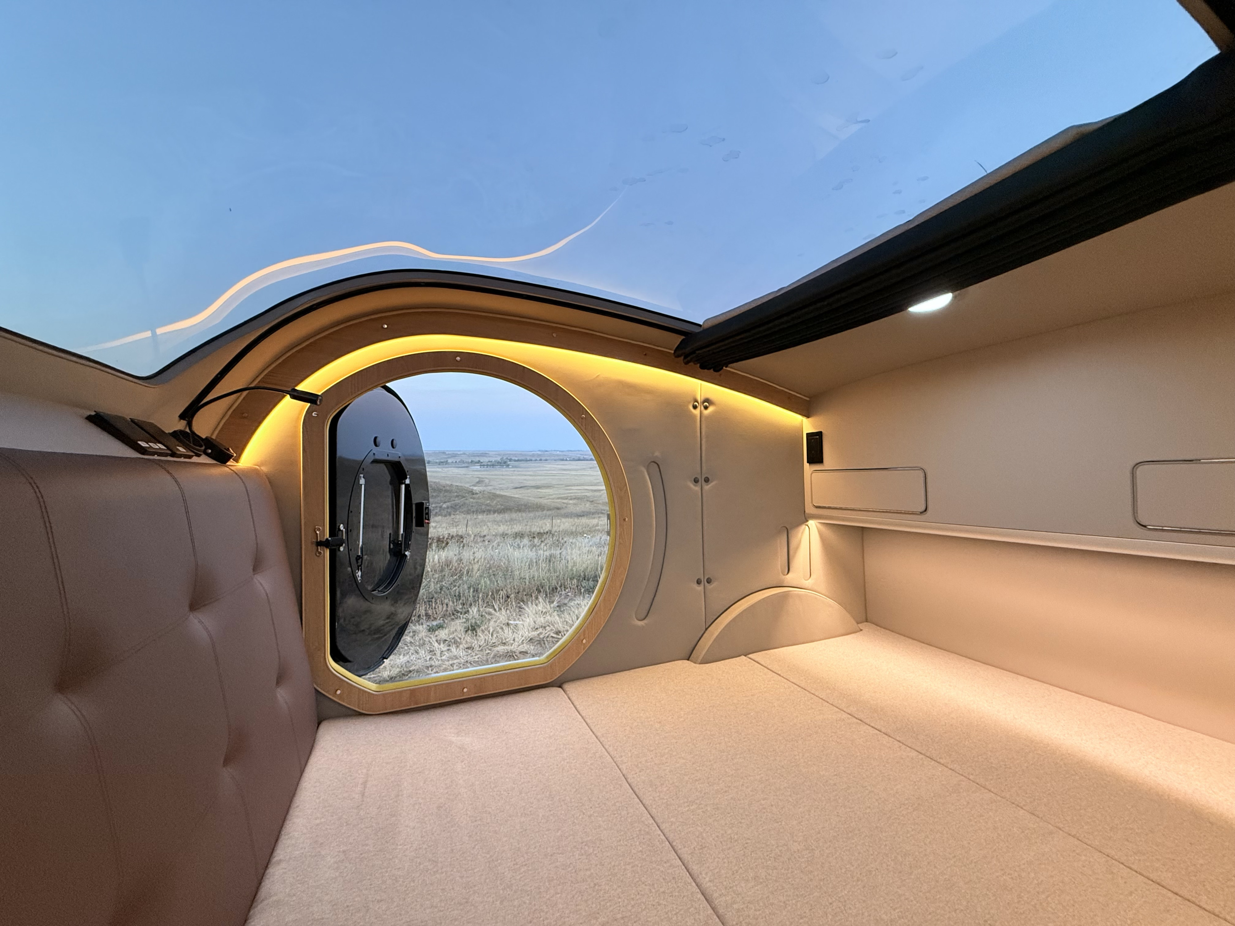 Cozy RV rental interior with a panoramic roof and a unique porthole window overlooking scenic fields.. Hebei On The Road Comma-E 2024