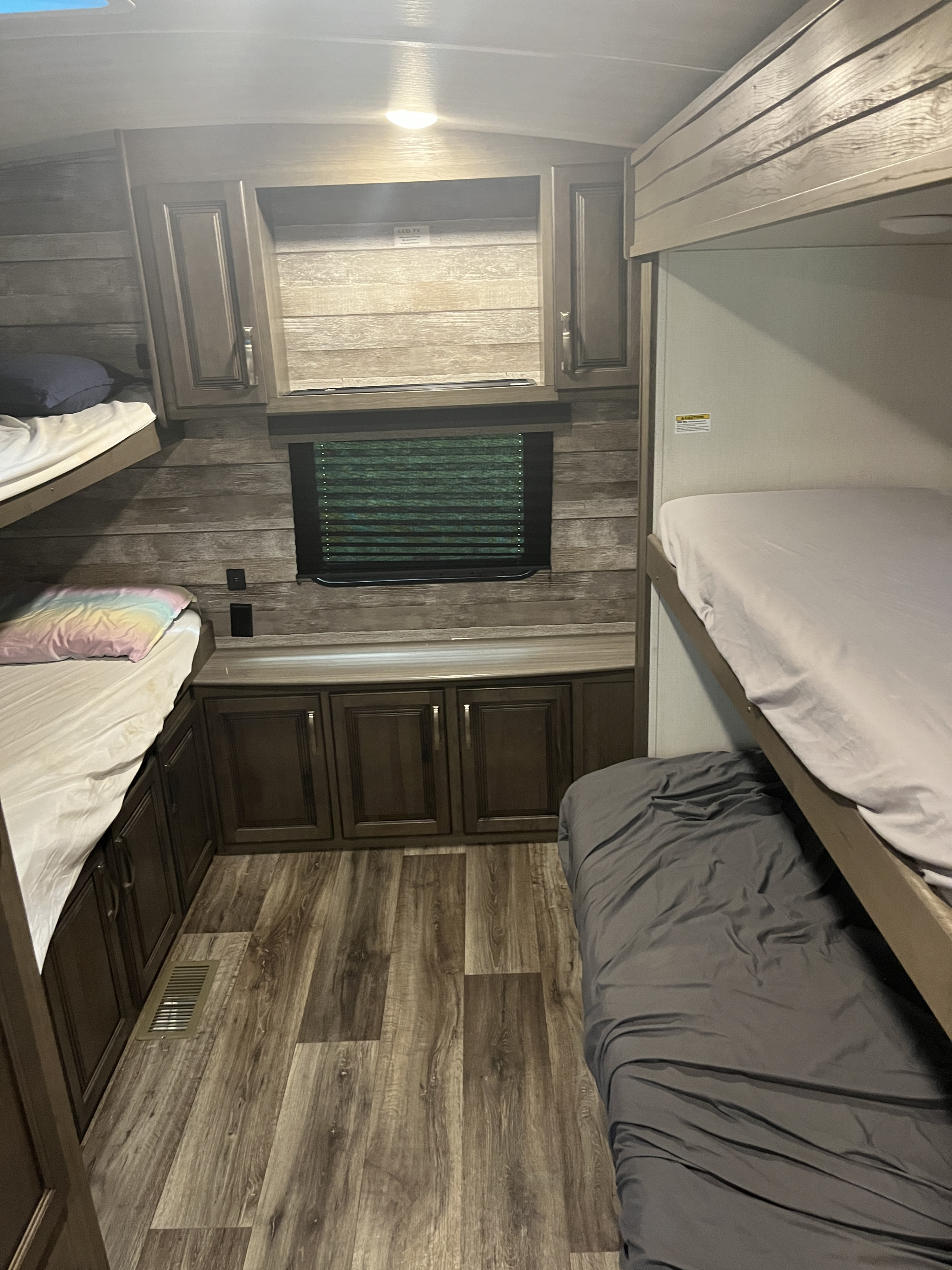 RV rental bunkhouse: Interior with four beds, wood-look walls, window with blind, and storage cabinets.. Keystone RV Cougar 2021