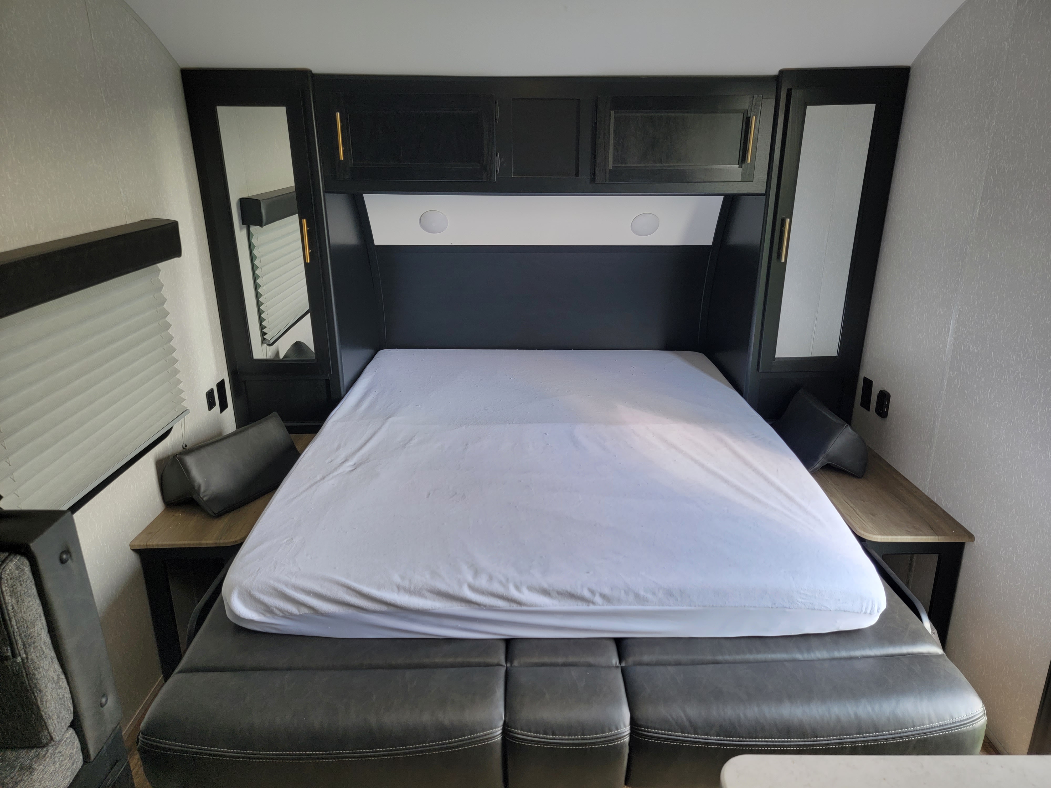 RV rental bedroom: a smart design with a bed over a convertible sofa, overhead storage, and integrated side tables.. Forest River Cherokee Grey Wolf 2022