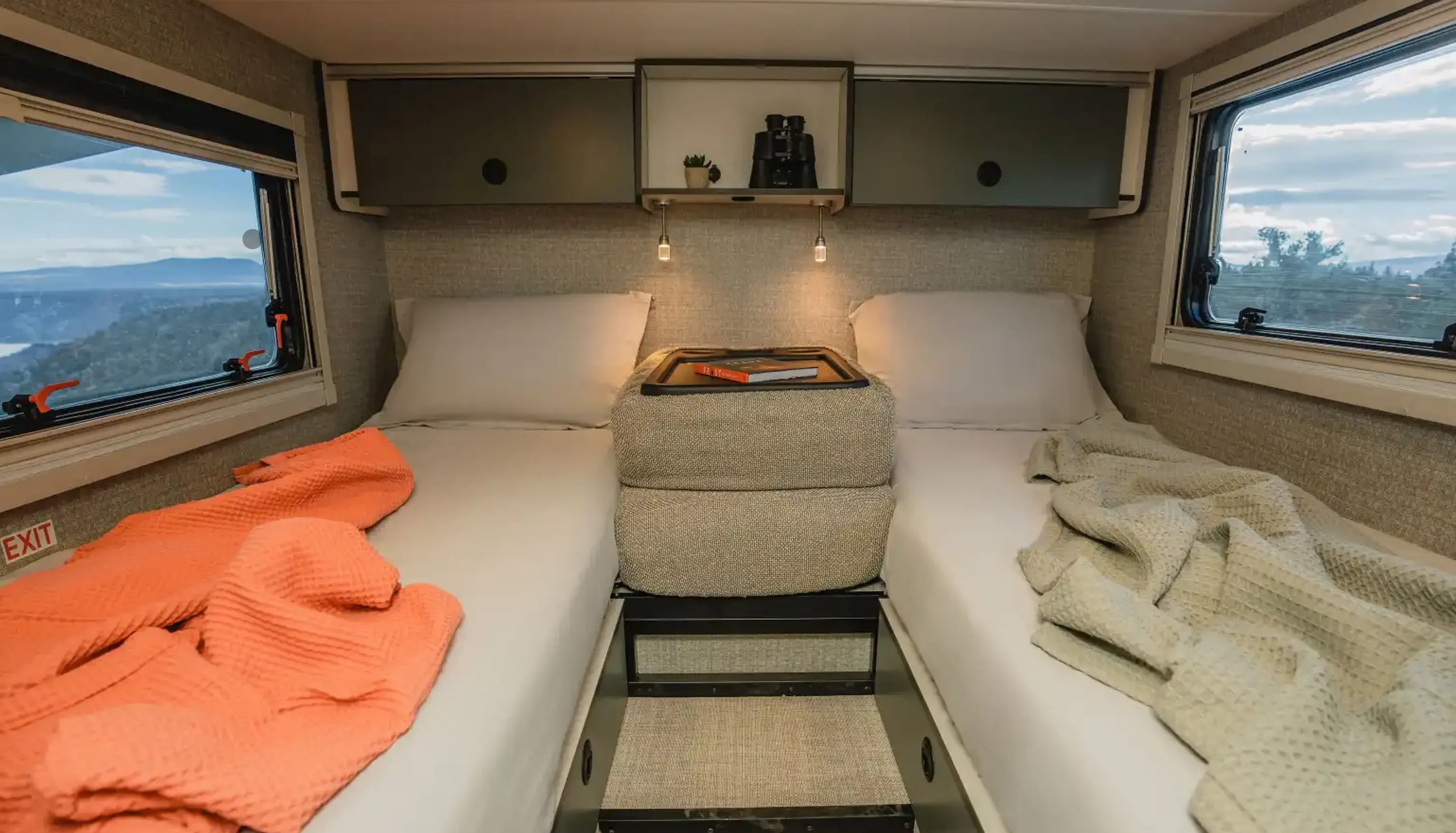 Cozy RV rental bedroom showing twin beds, overhead storage, and stunning window views.. Winnebago Ekko 2025