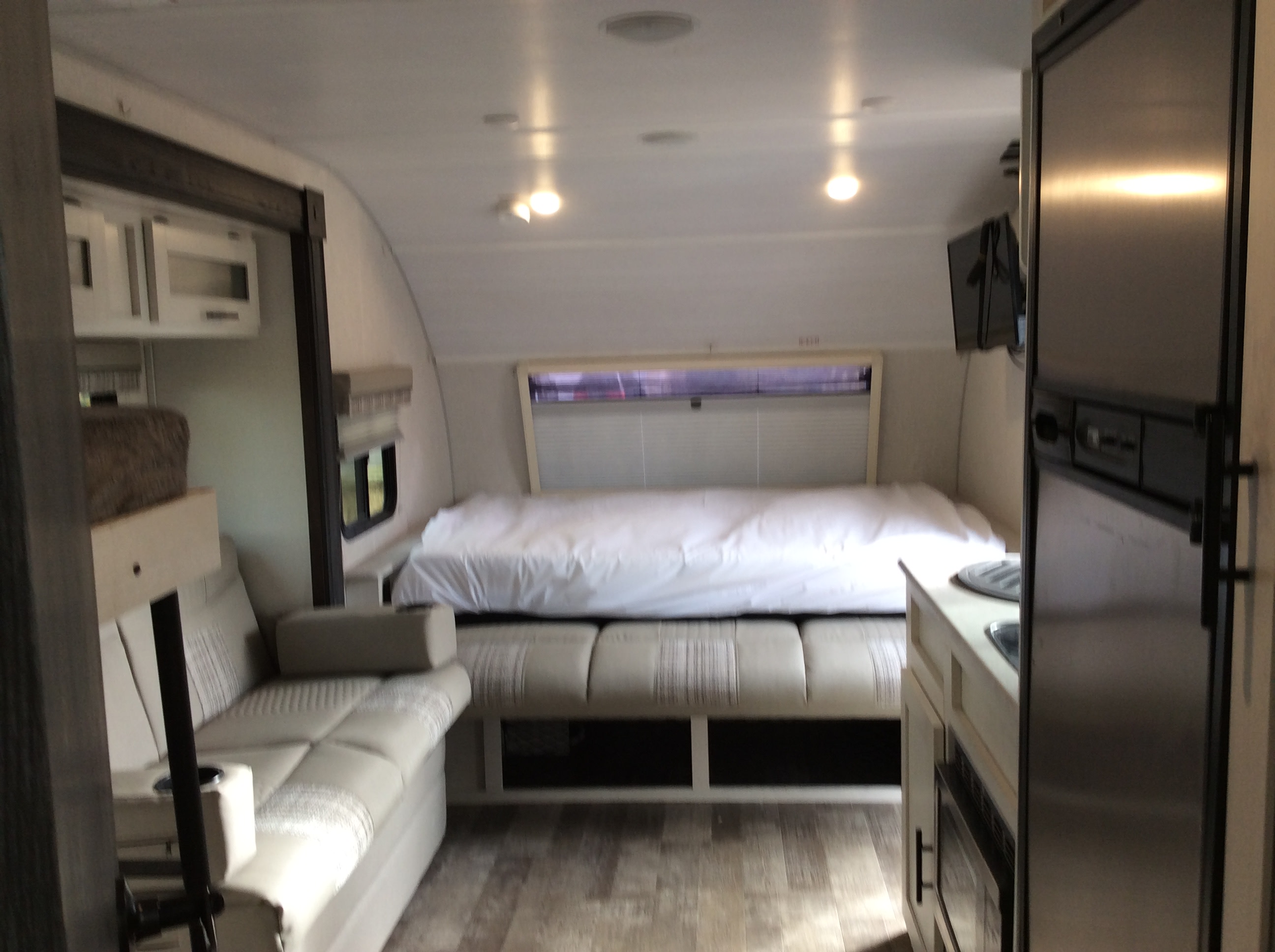 Step into this RV rental's modern interior: a bed, lounge seating, and compact kitchen are visible, perfect for travel.. Forest River R-Pod 193 2021