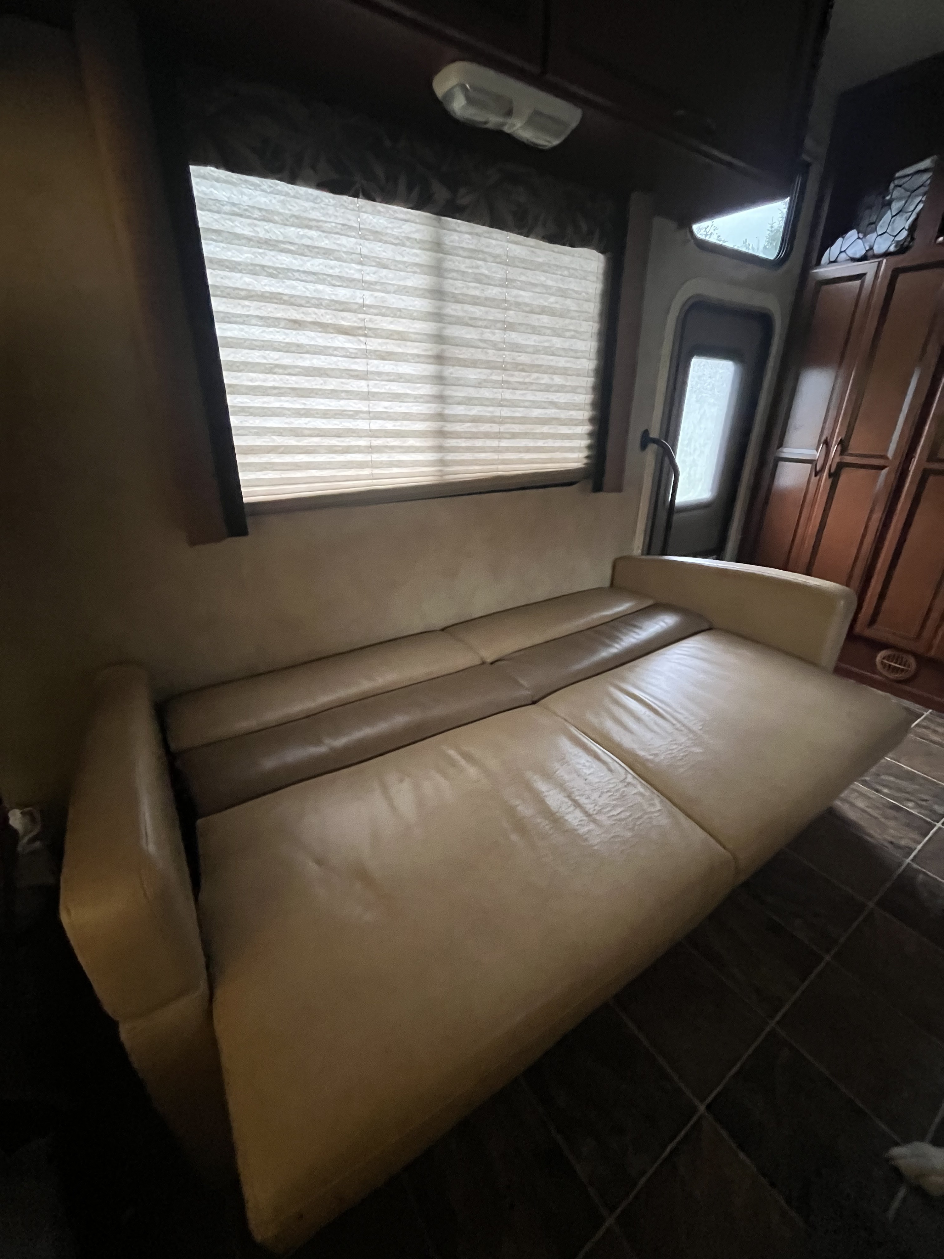 This RV rental features a practical interior with a light-colored convertible sofa bed, window, and wood cabinets.. A.C.E. A.C.E. Motorhome 2013