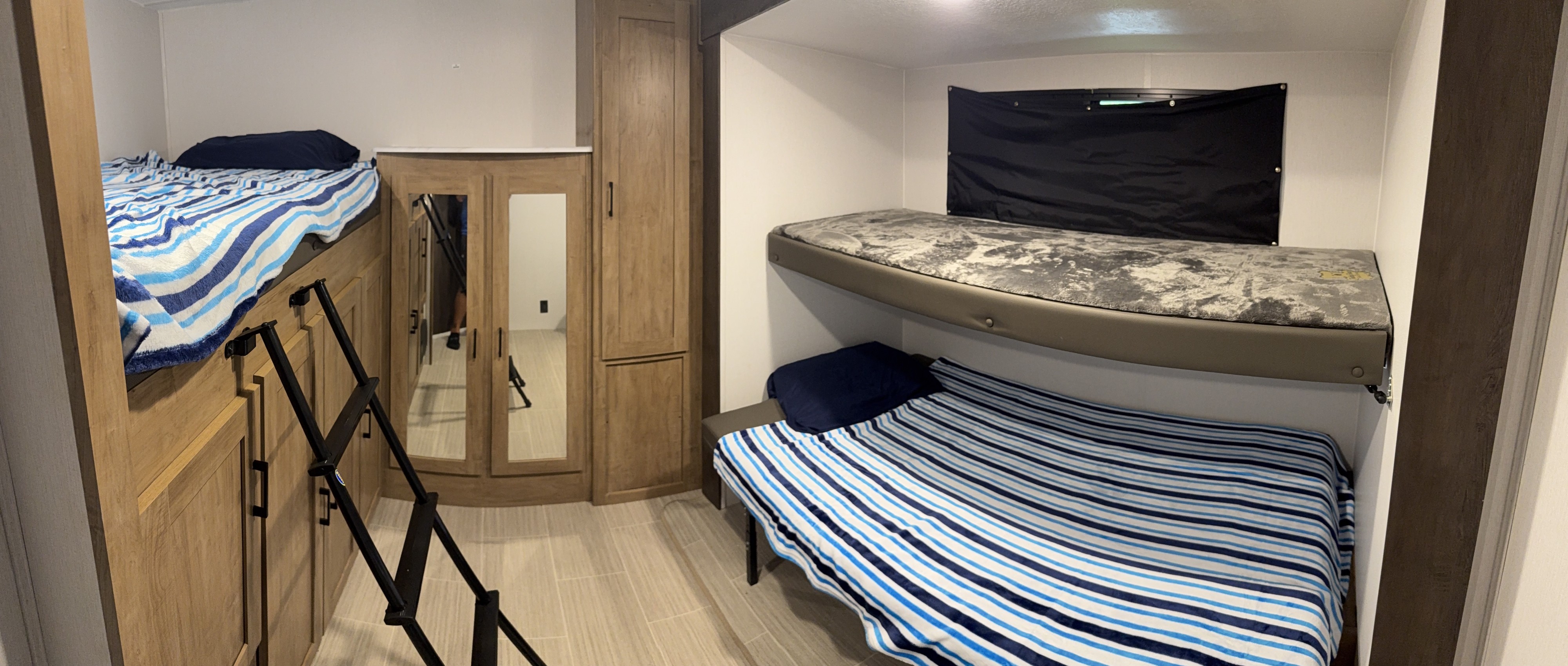 This RV rental interior features multiple bunk beds, a ladder, blue and white striped bedding, and mirrored storage.. Coachmen Express 2024