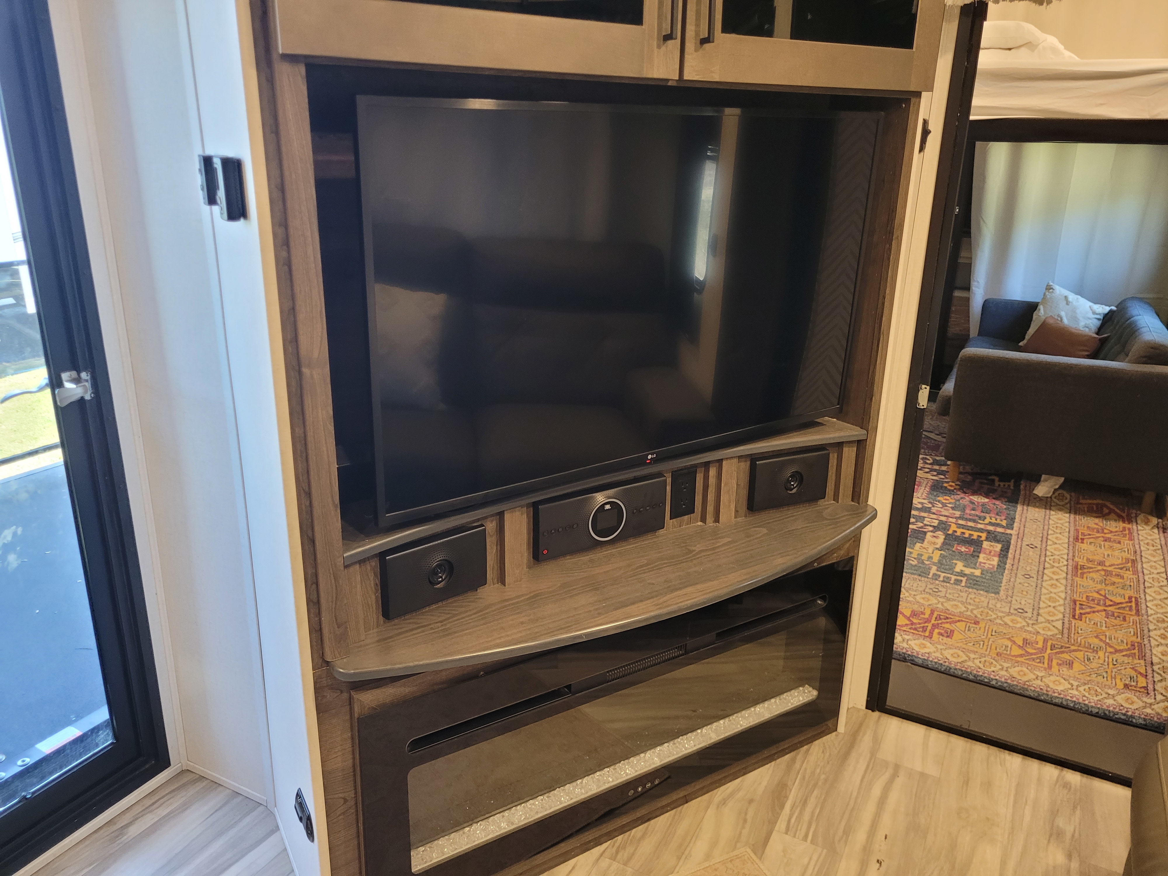 Modern RV rental interior featuring a TV entertainment center with a JBL sound system and electric fireplace, creating a cozy living space.. Alliance Valor 2023
