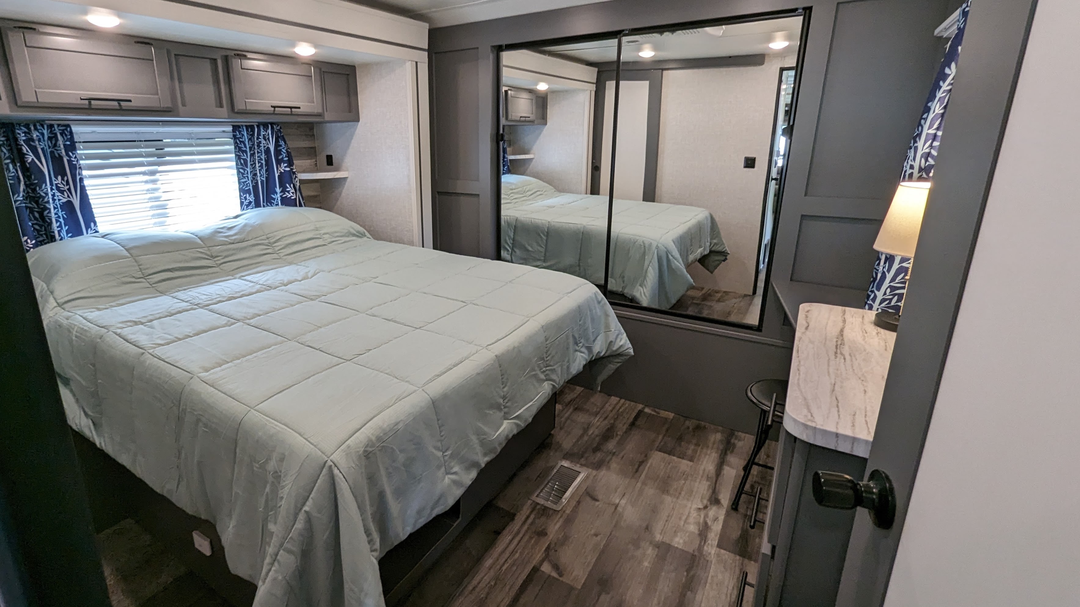 Relax in this modern RV rental bedroom featuring a comfortable bed, overhead storage, and mirrored closet.. Crossroads RV Volante 2022