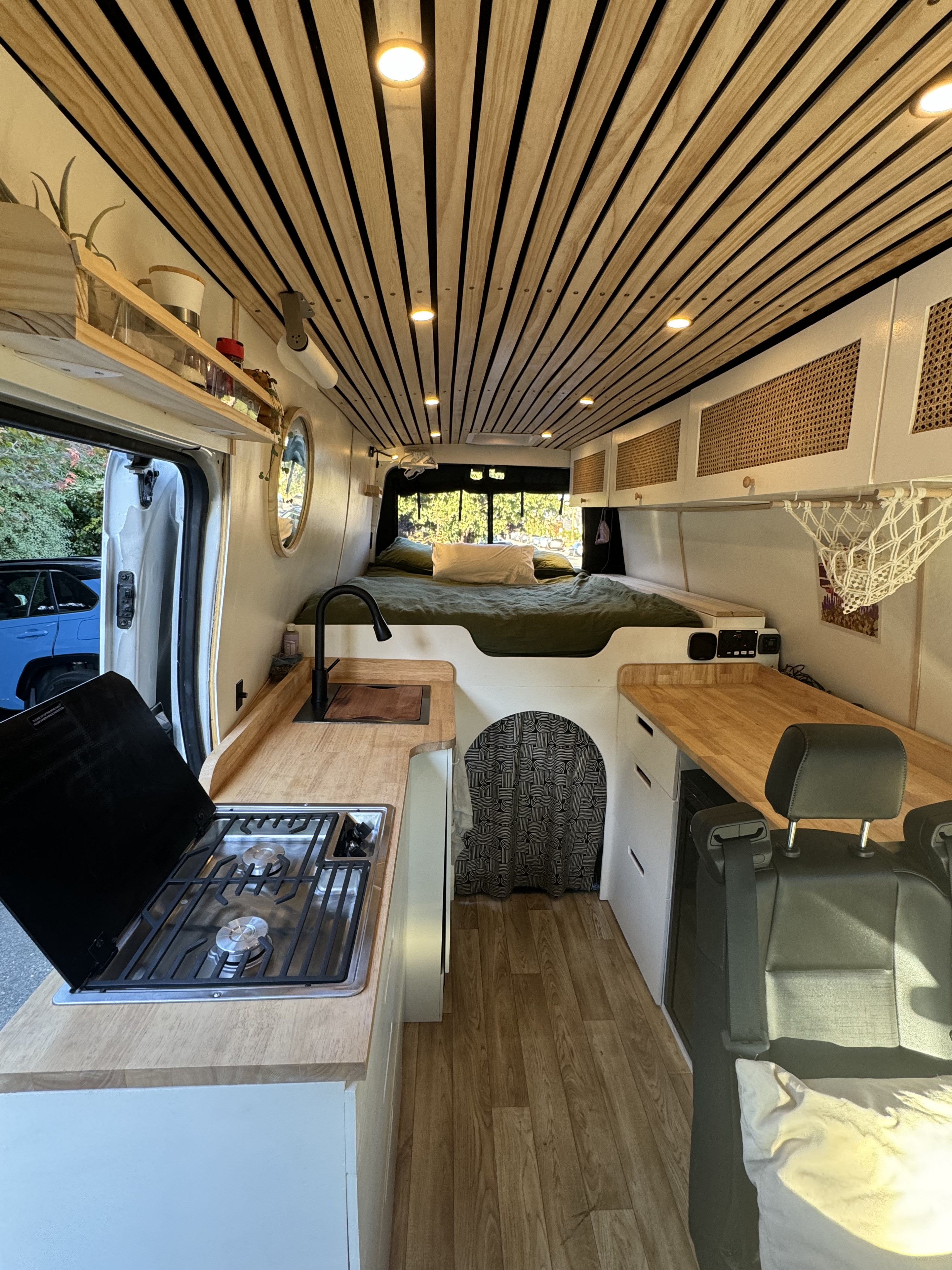 This RV rental features a custom camper van interior, complete with a functional kitchen, cozy bed, and stylish wood-slatted ceiling.. Ford Transit 2020
