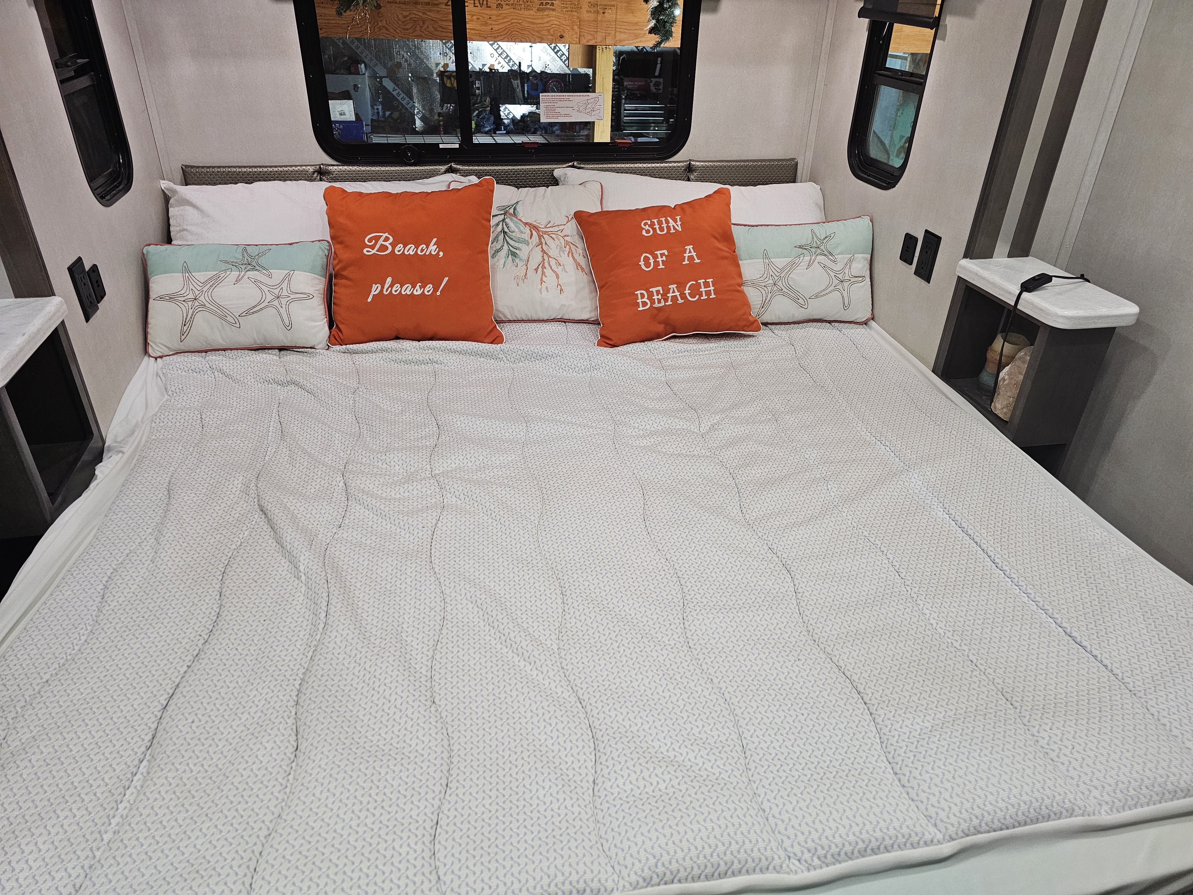Cozy RV rental bedroom featuring a made bed with a patterned comforter and fun beach-themed pillows.. Georgetown GT7 2022