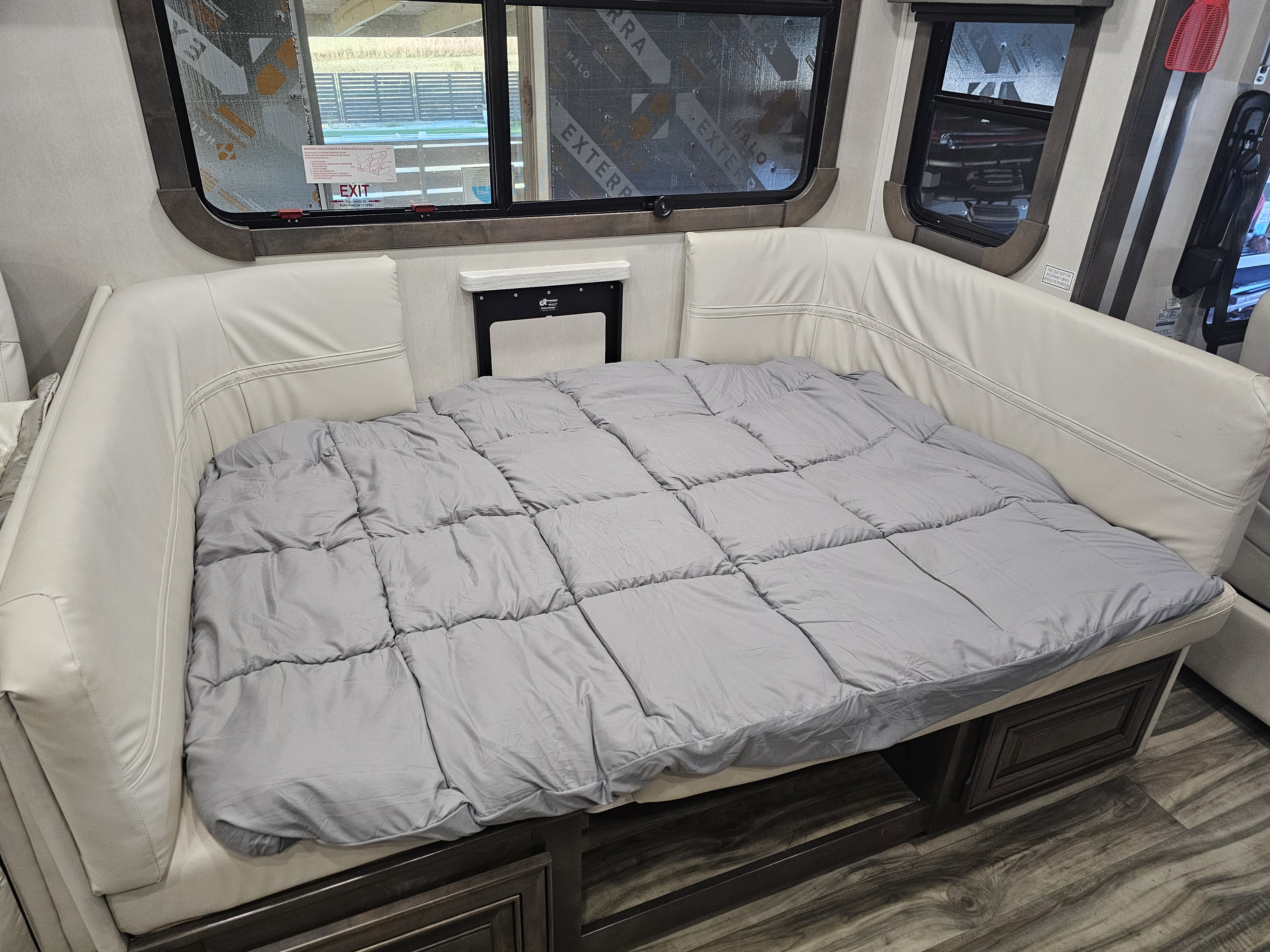Cozy RV rental interior: U-shaped dinette transforms into a bed, with safety labels on panoramic windows.. Georgetown GT7 2022