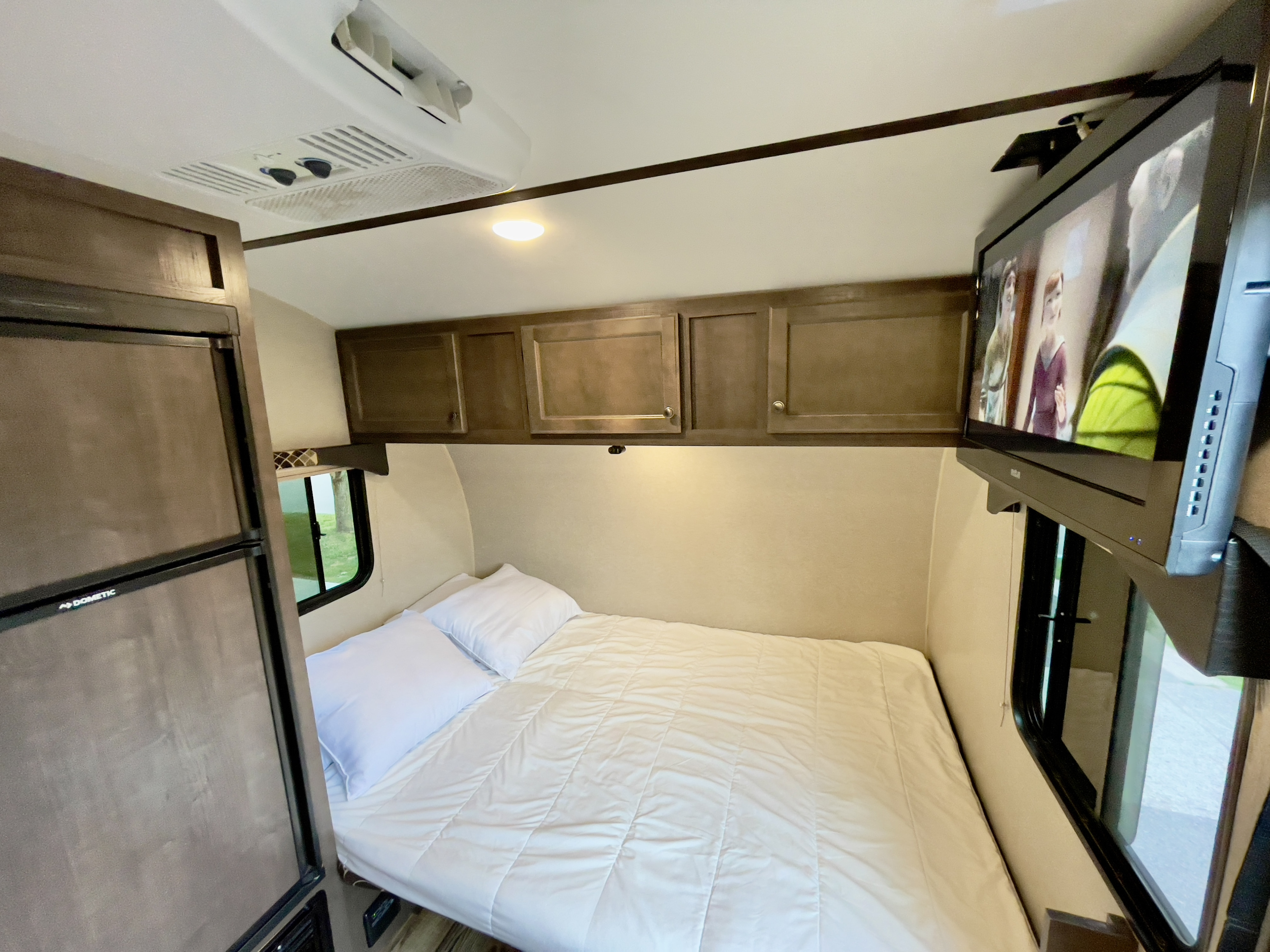 RV rental interior: queen bed, overhead cabinets, AC, fridge, TV. A cozy space for your next road trip adventure!. Sunset Park RV Sun Lite 2019
