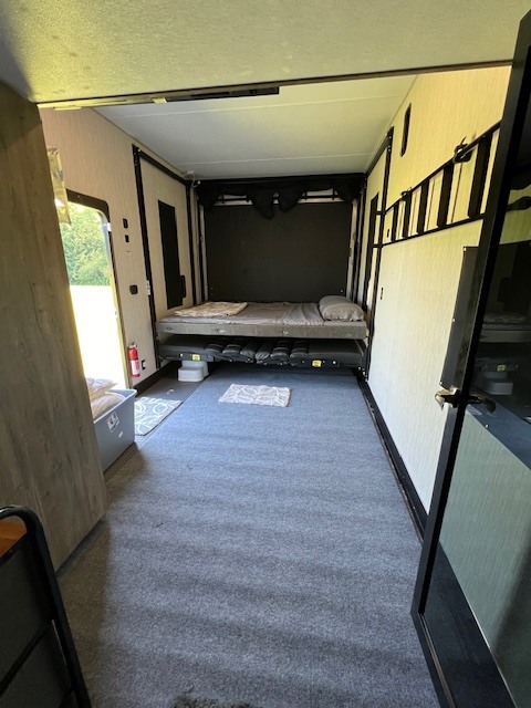 RV rental interior: a toy hauler's versatile garage with lowered bed and upper bunk. Grey carpeted floor.. Forest River Cherokee Wolf Pack Toy Hauler 2020