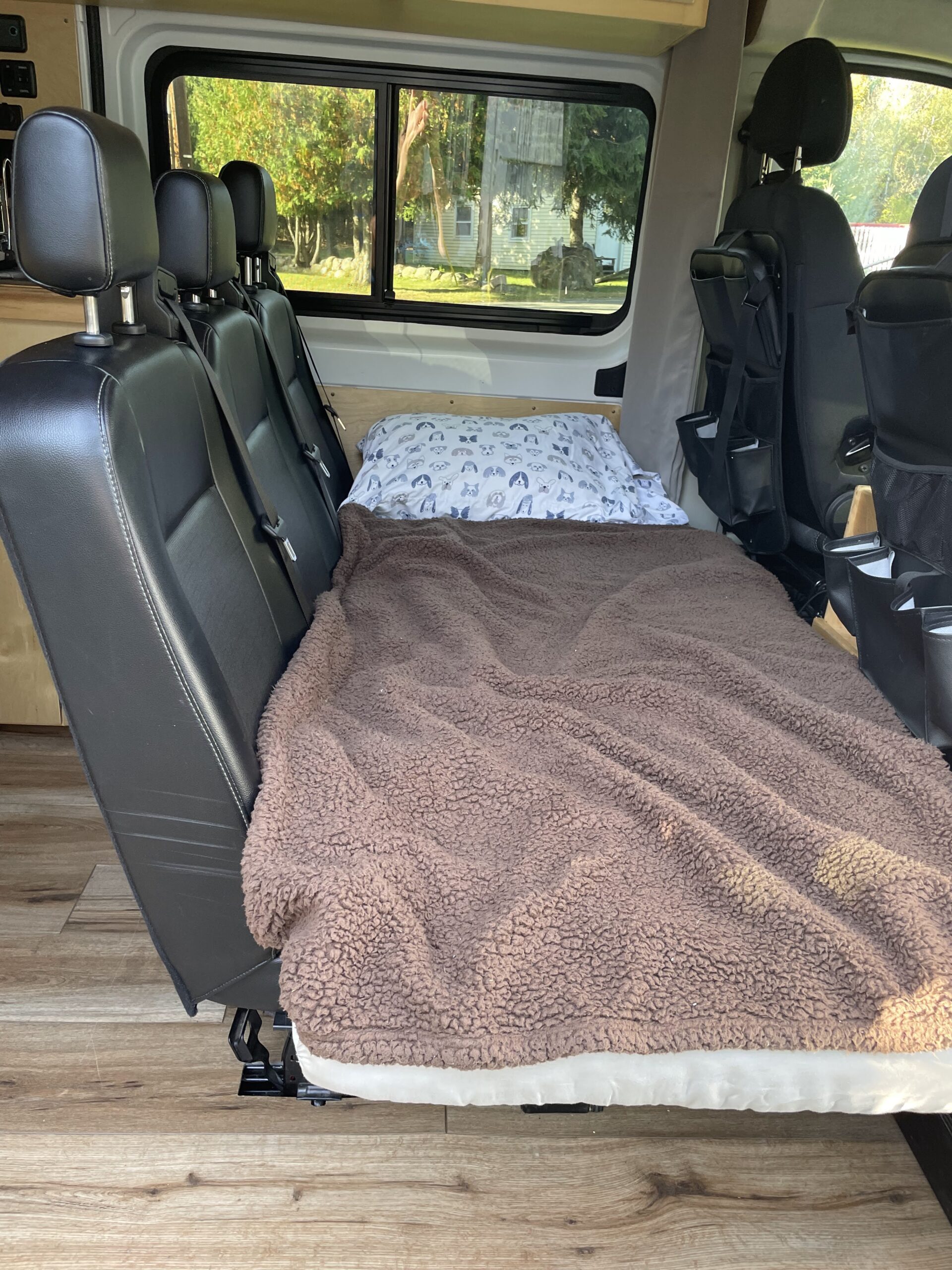 Cozy RV rental interior: fold-down seats create a bed with a dog-patterned pillow and fuzzy blanket, ready for your road trip.. Dodge Ram 1500 2020