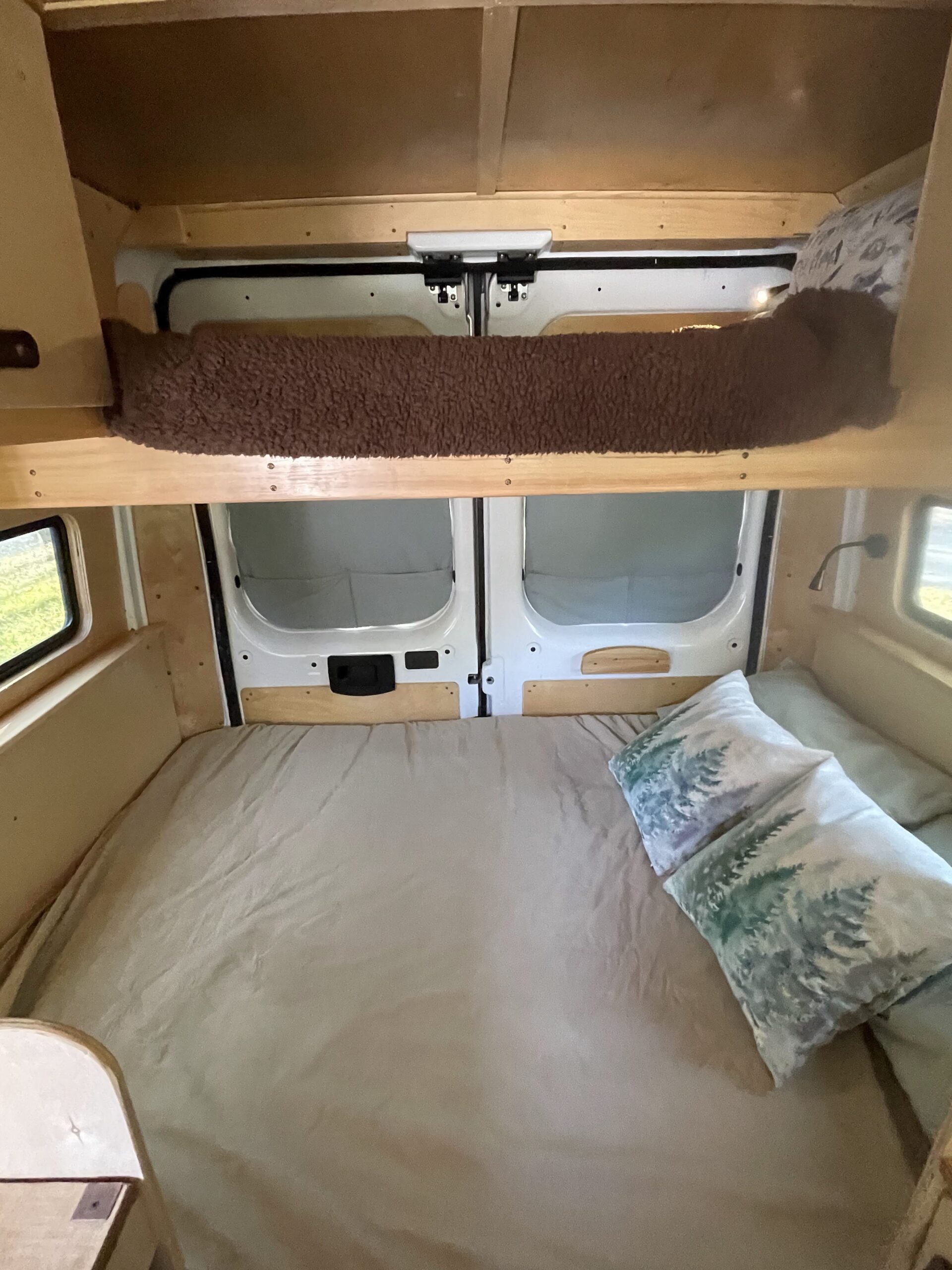 RV rental: Interior view of a custom-built camper van with a cozy bed and overhead bunk for storage.. Dodge Ram 1500 2020