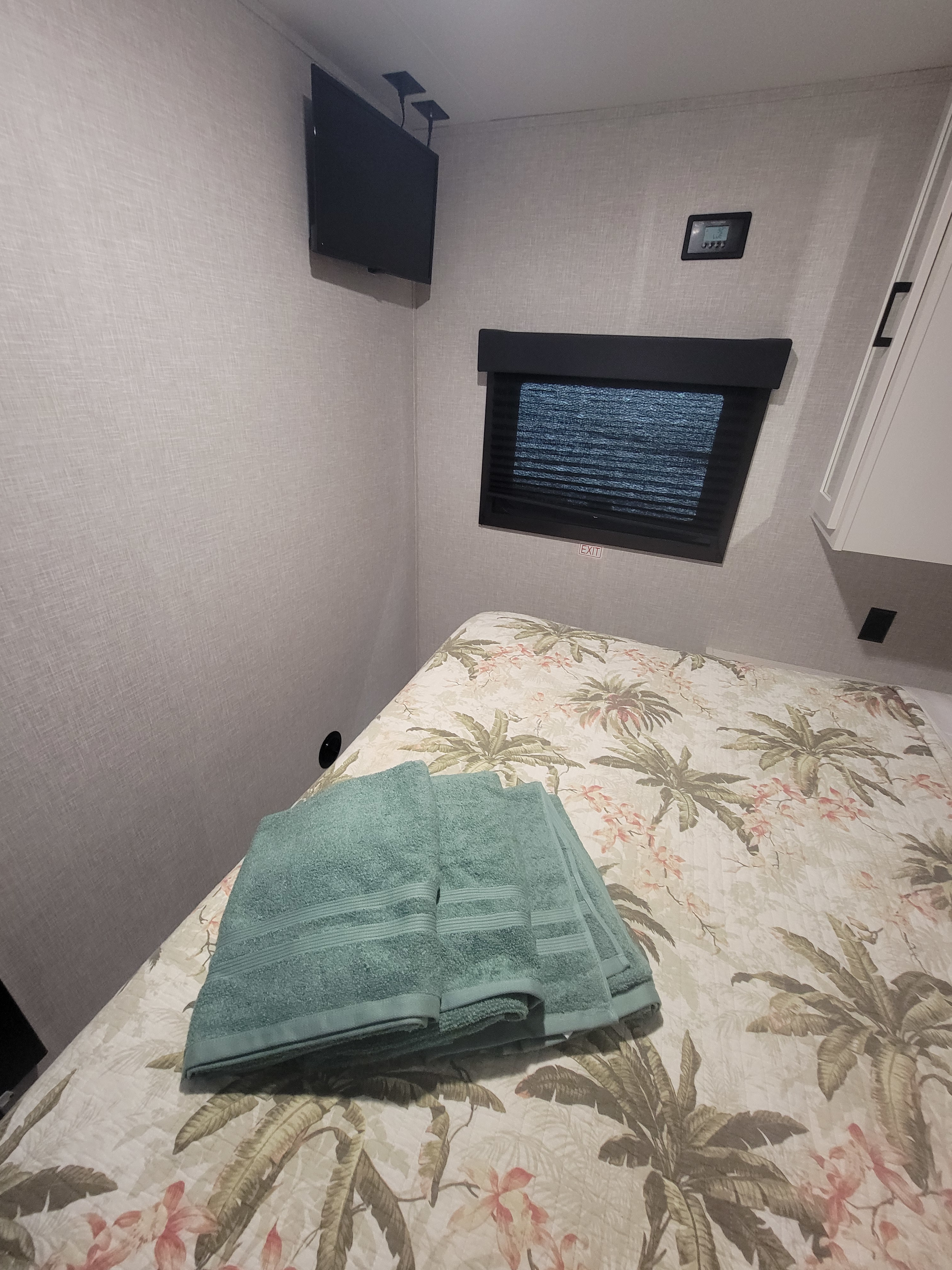 RV rental bedroom featuring tropical bedding, fresh towels, wall-mounted TV, & control panel.. Starcraft Autunm Ridge 26bh 2024
