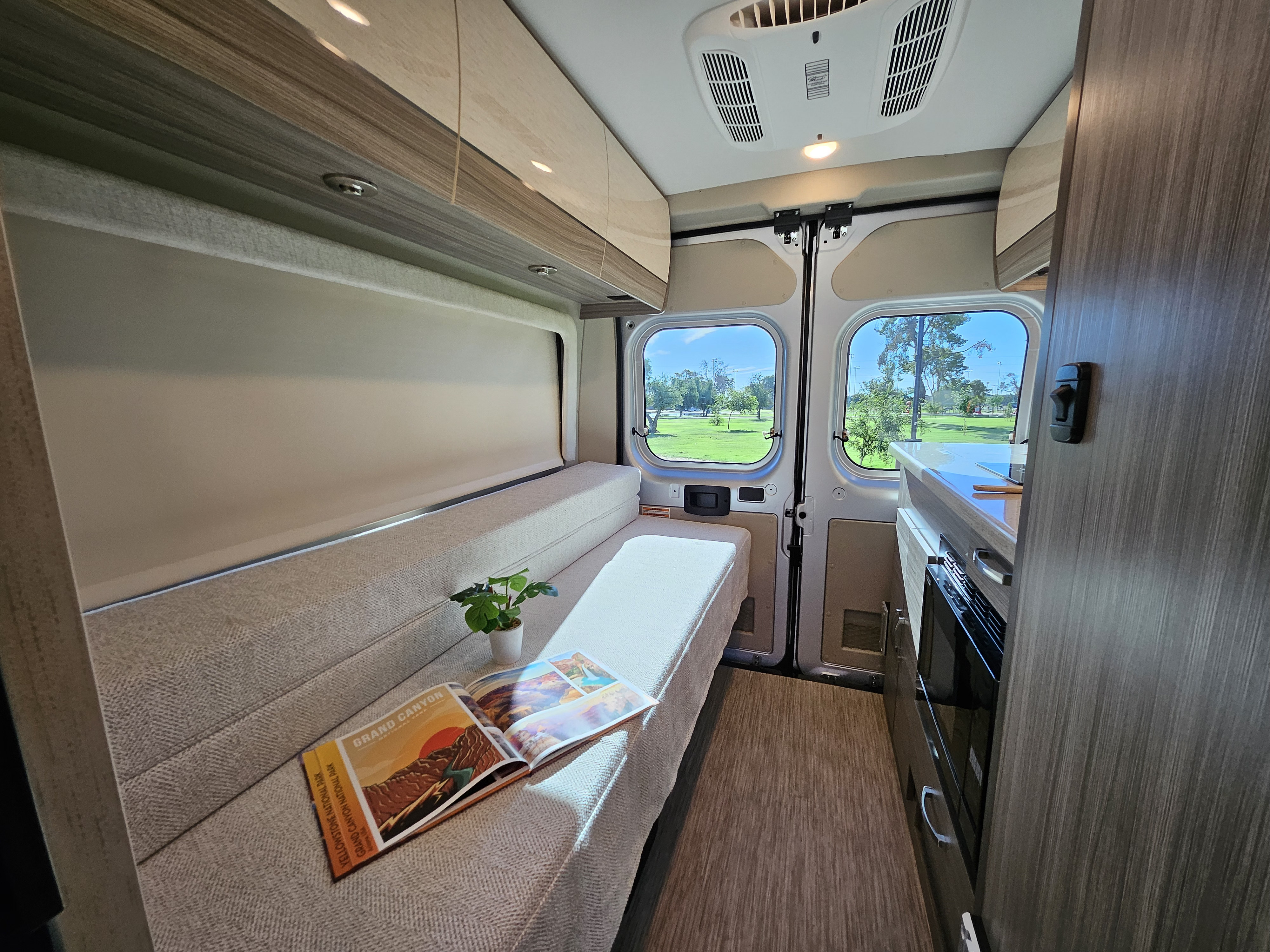 Cozy RV rental interior featuring a convertible bench bed, kitchenette, and bright windows for your next adventure.. Entegra Coach Ethos 2024