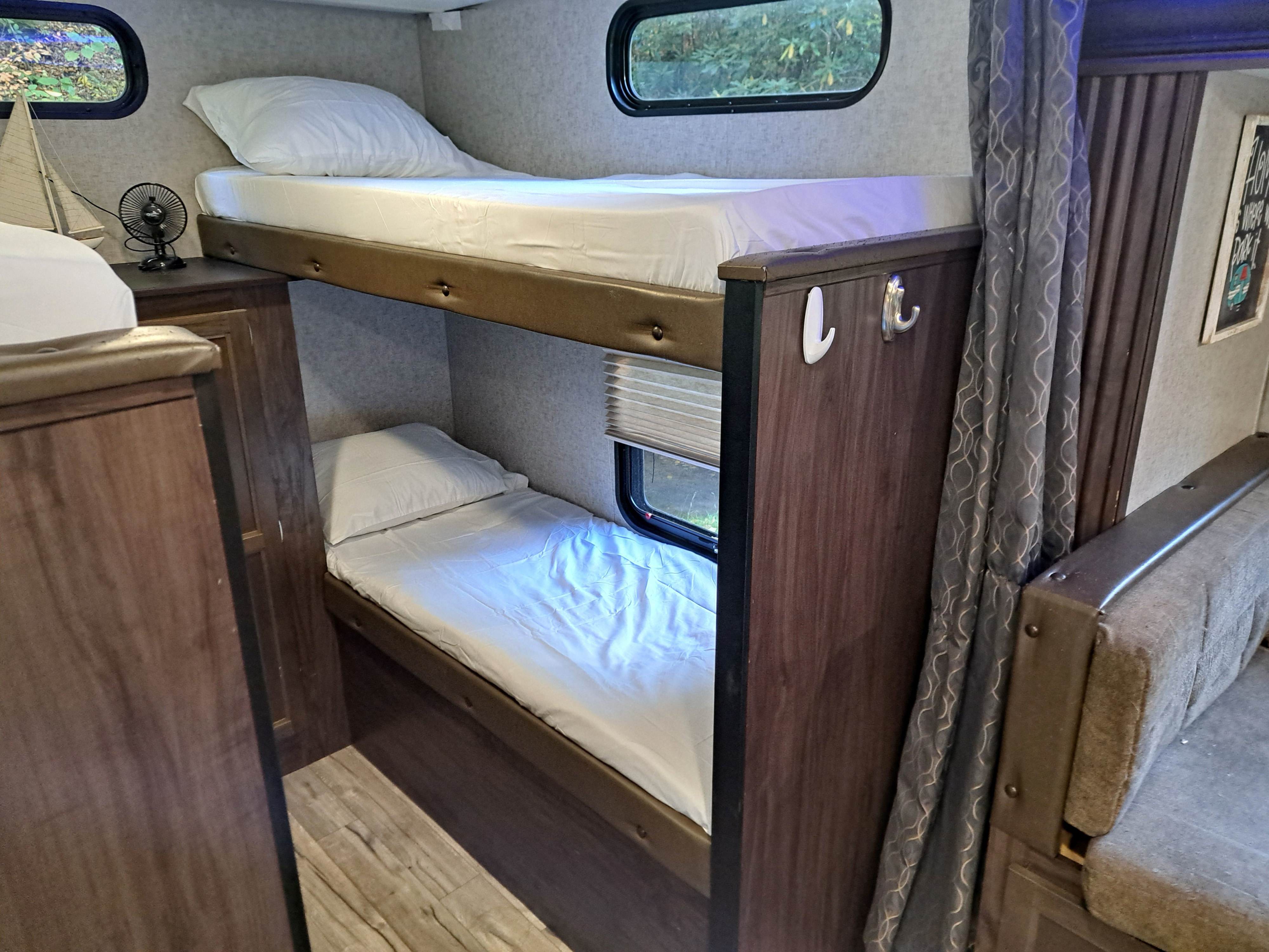 This RV rental features comfy bunk beds with white linens, windows, and practical storage hooks.. Forest River Cherokee Grey Wolf 2019