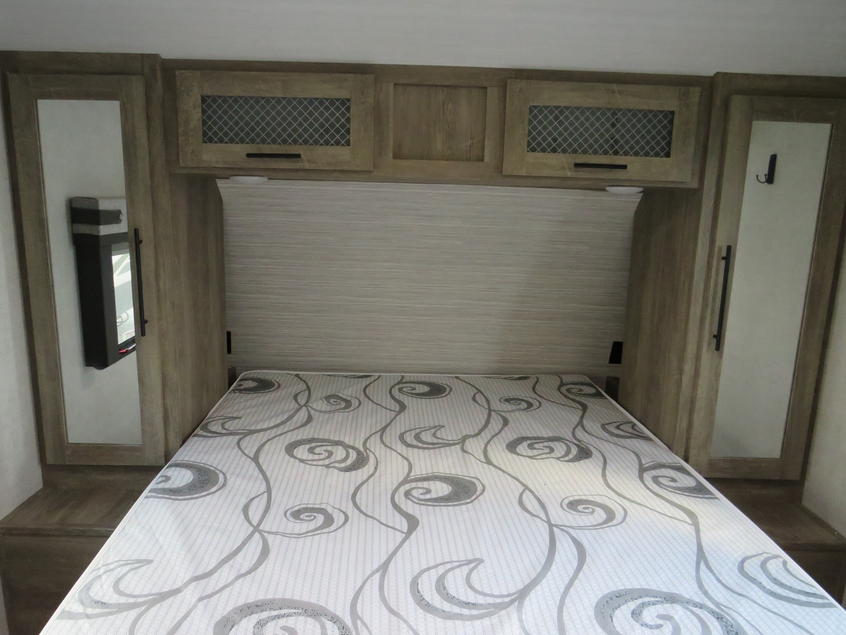 This RV rental bedroom features a comfy bed, overhead storage cabinets, and mirrored side closets for practical living.. Forest River Heritage Glen 2021