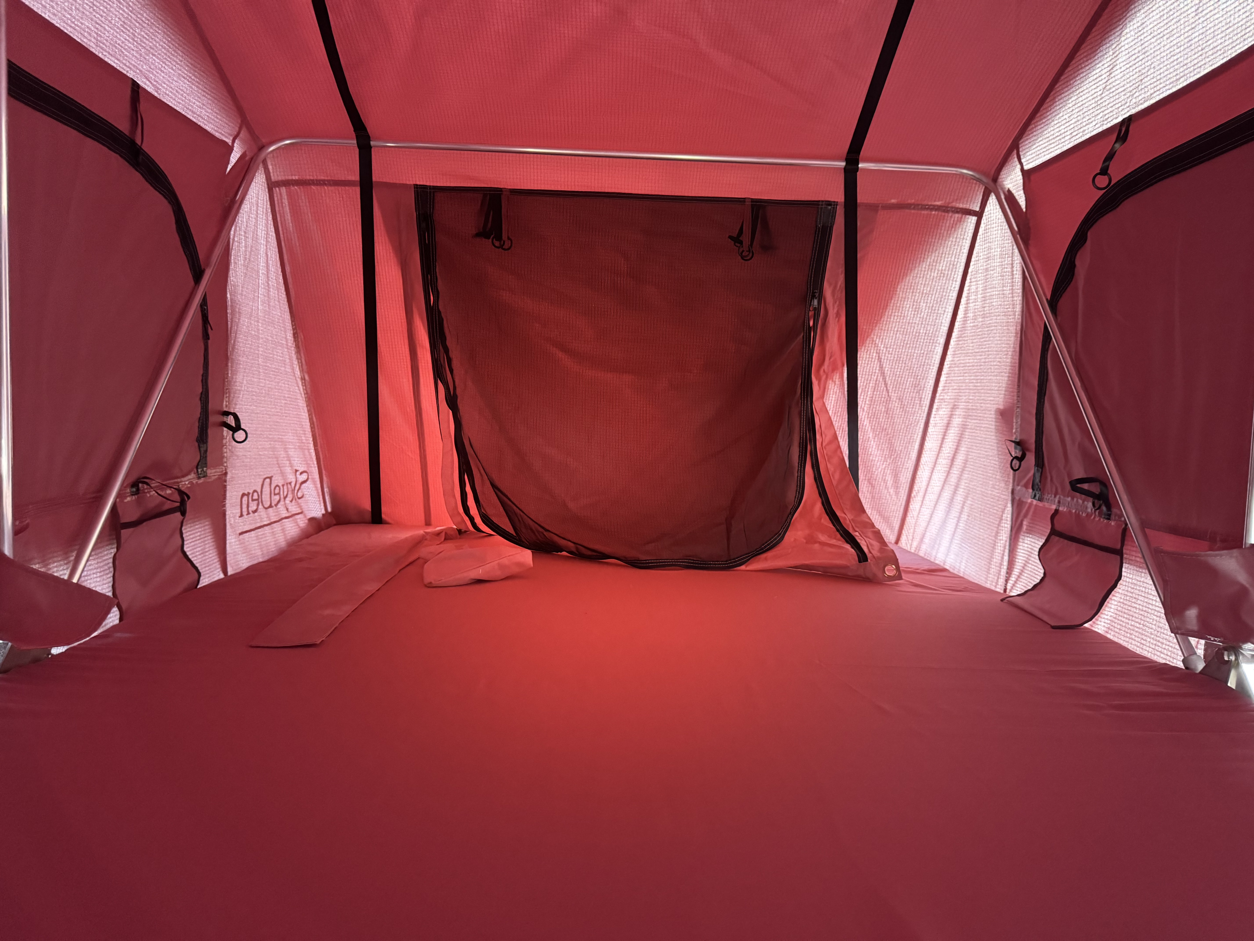 Inside a spacious red rooftop tent, perfect for your RV rental camping trip. Features include a comfy bed, mesh windows, & pockets.. Modern Little Buggy 12LRK 2025