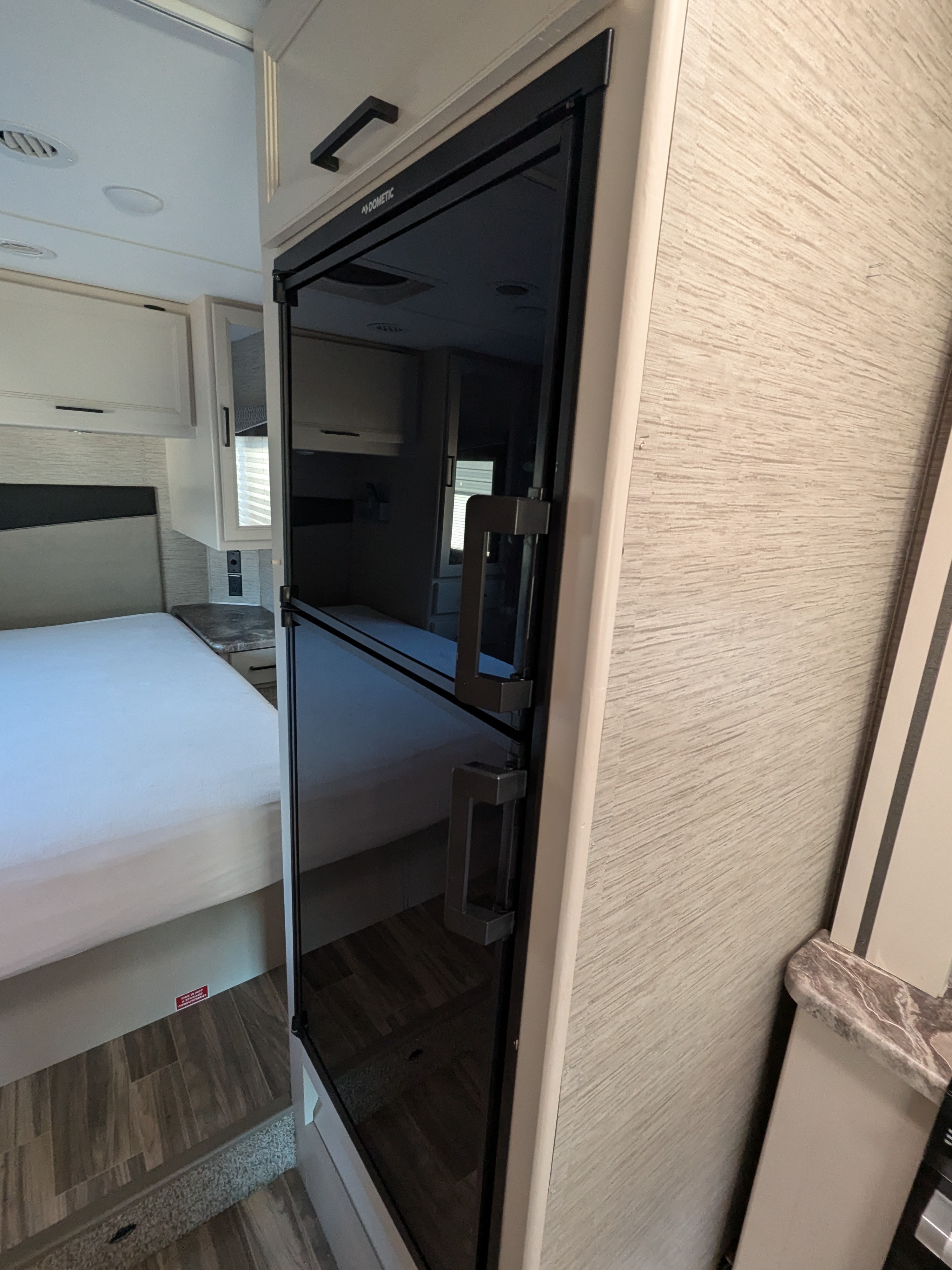Spacious RV rental interior with a Dometic fridge/freezer, comfy bed, and overhead storage.. Thor Motor Coach Four Winds 2022