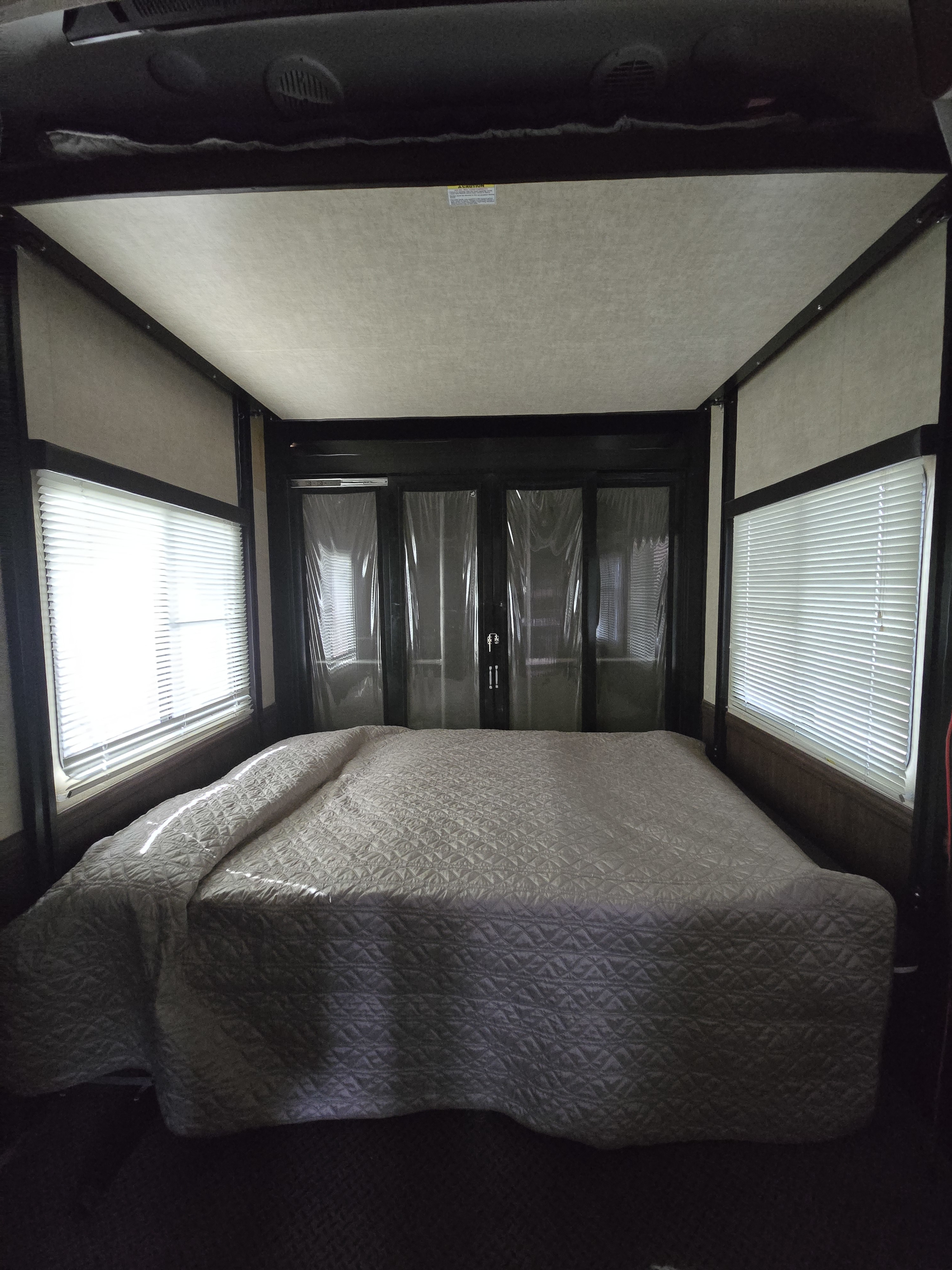 Experience comfort in this RV rental's spacious bedroom featuring a quilted bed and bright windows.. Heartland RVs Cyclone HD Edition Toy Hauler 2015