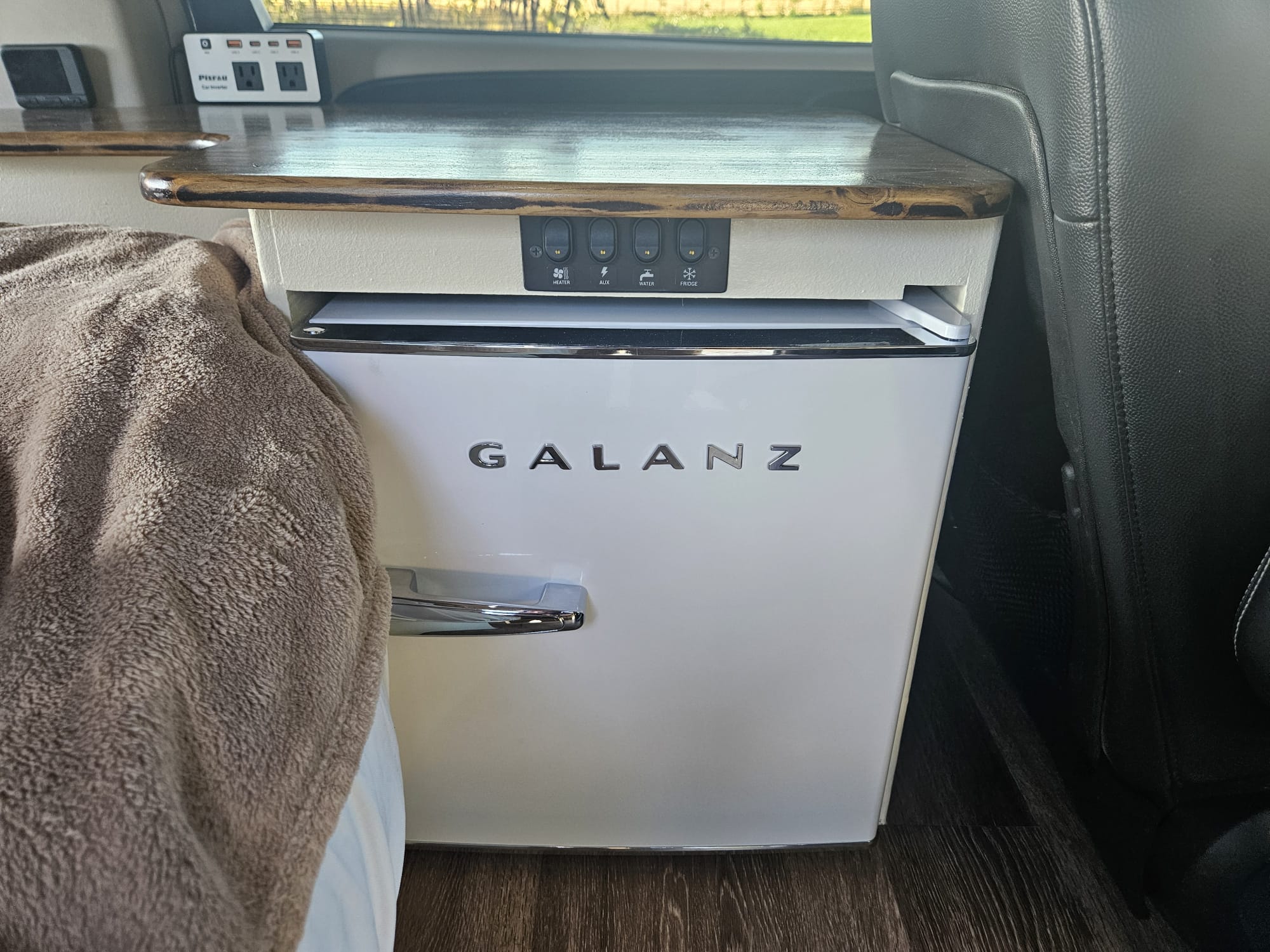 RV rental interior: A white Galanz mini-fridge sits below a control panel with heater, aux, water, & fridge switches.. Chrysler Town Country 2013
