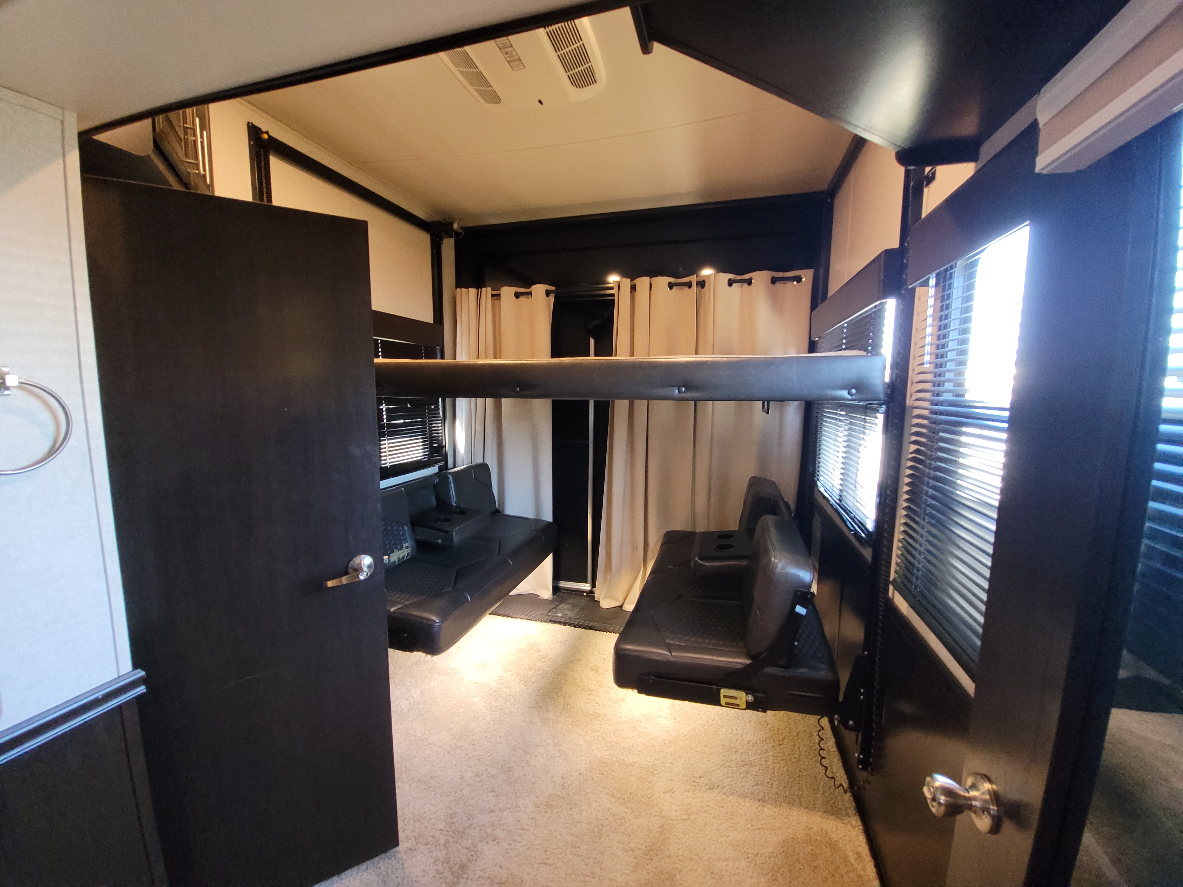 RV rental bedroom showing a bed with plaid sheets, built-in cabinets, and window. Features outlets & fire extinguisher.. Jayco Seismic 2017