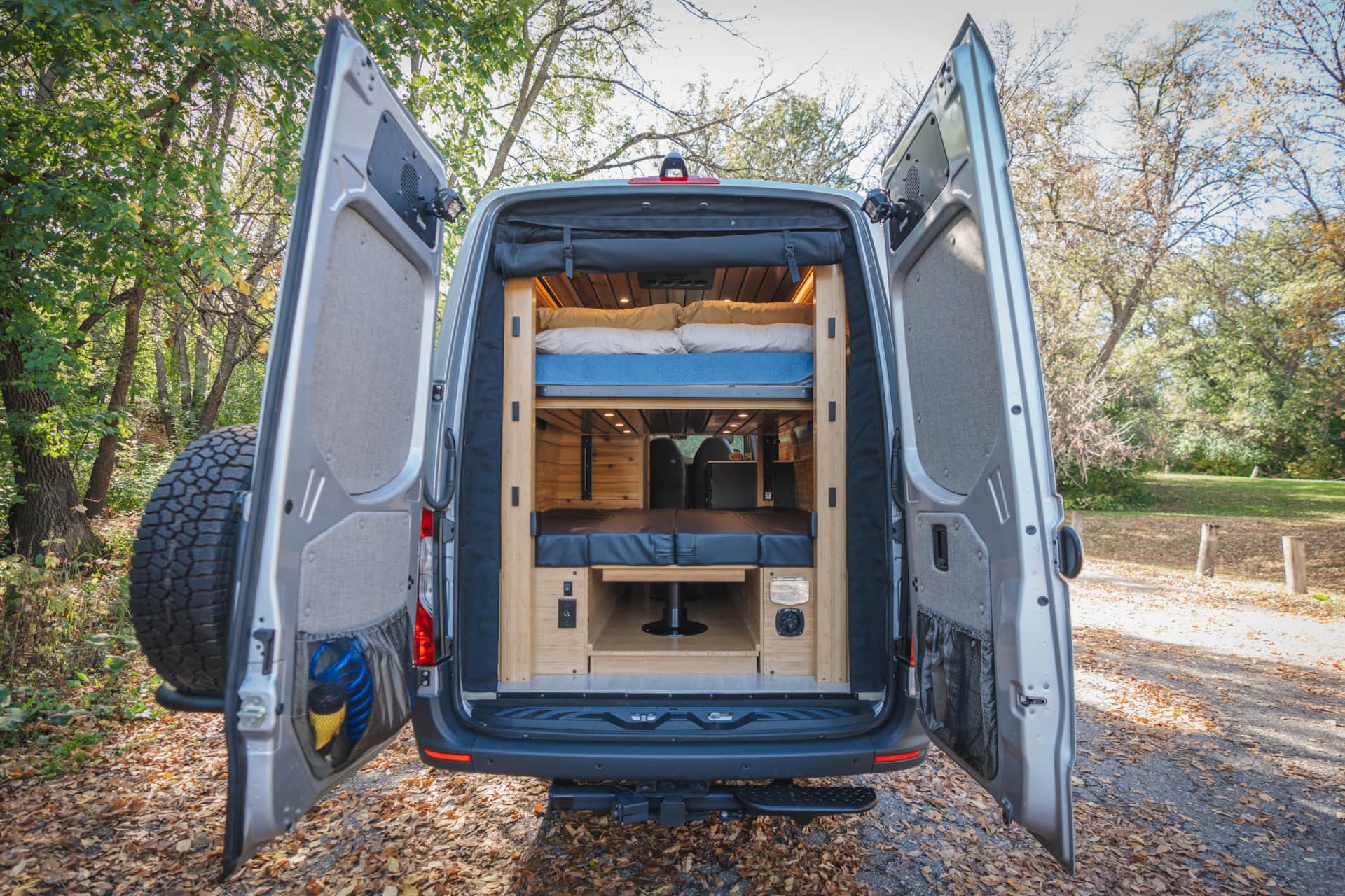 RV rental camper van's open rear reveals a two-tier bunk bed interior, perfect for comfortable road trip adventures.. Mercedes Sprinter 2023