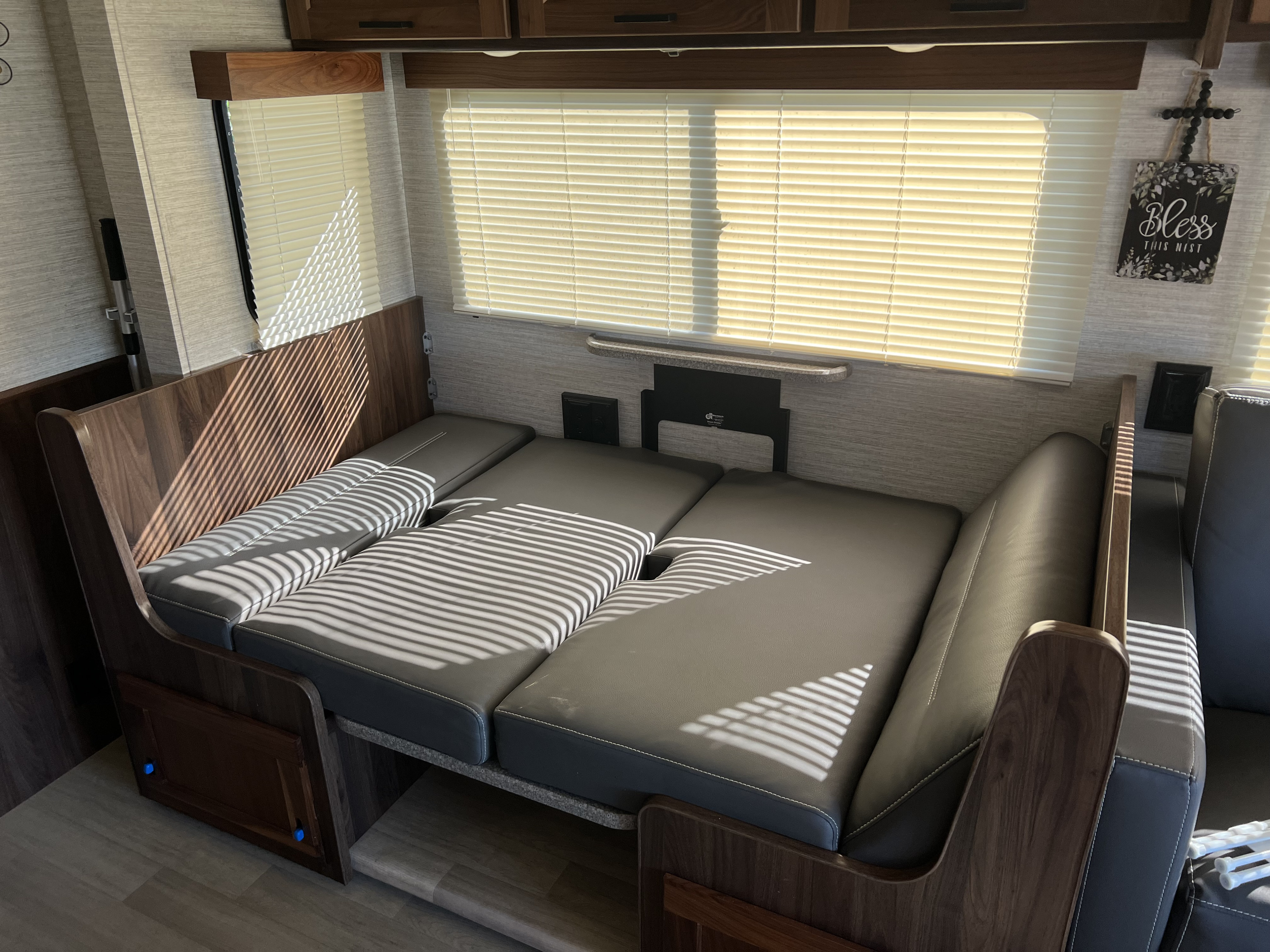 This RV rental features a convertible dinette transformed into a sleeping area. Grey cushions and wood tones create a cozy RV interior.. Winnebago Vista 2021