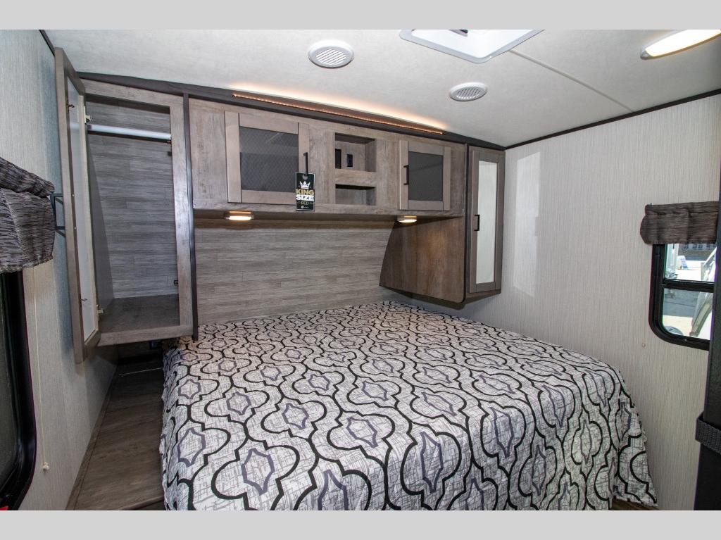 Discover a comfortable RV rental bedroom featuring a large, inviting bed, ample overhead storage, and a convenient wardrobe.. Heartland North Trail 2021