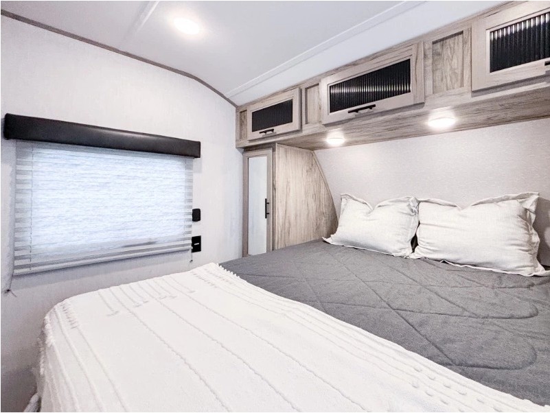 Cozy RV rental bedroom with comfortable bed, overhead storage, and window for a relaxing getaway.. Forest River Cherokee Alpha Wolf 2022