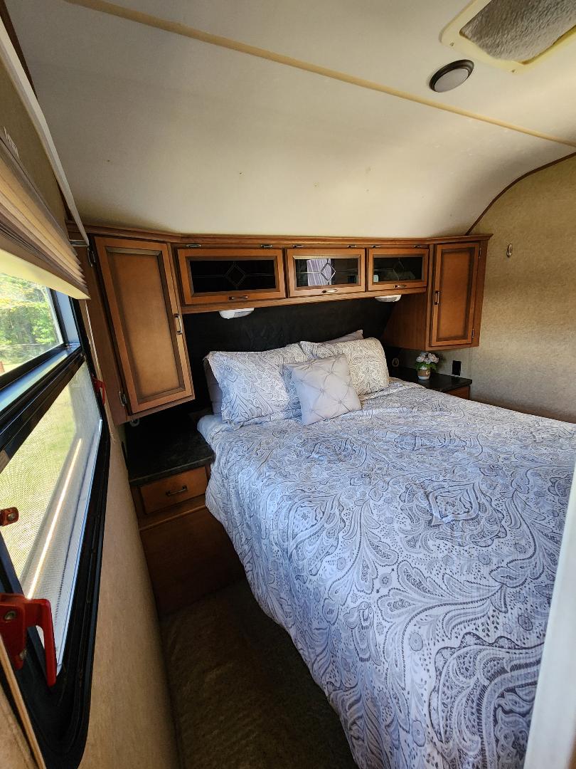 Cozy RV rental bedroom with a comfortable bed, overhead cabinets, and a window for natural light.. Crossroads RV Cruiser 2012