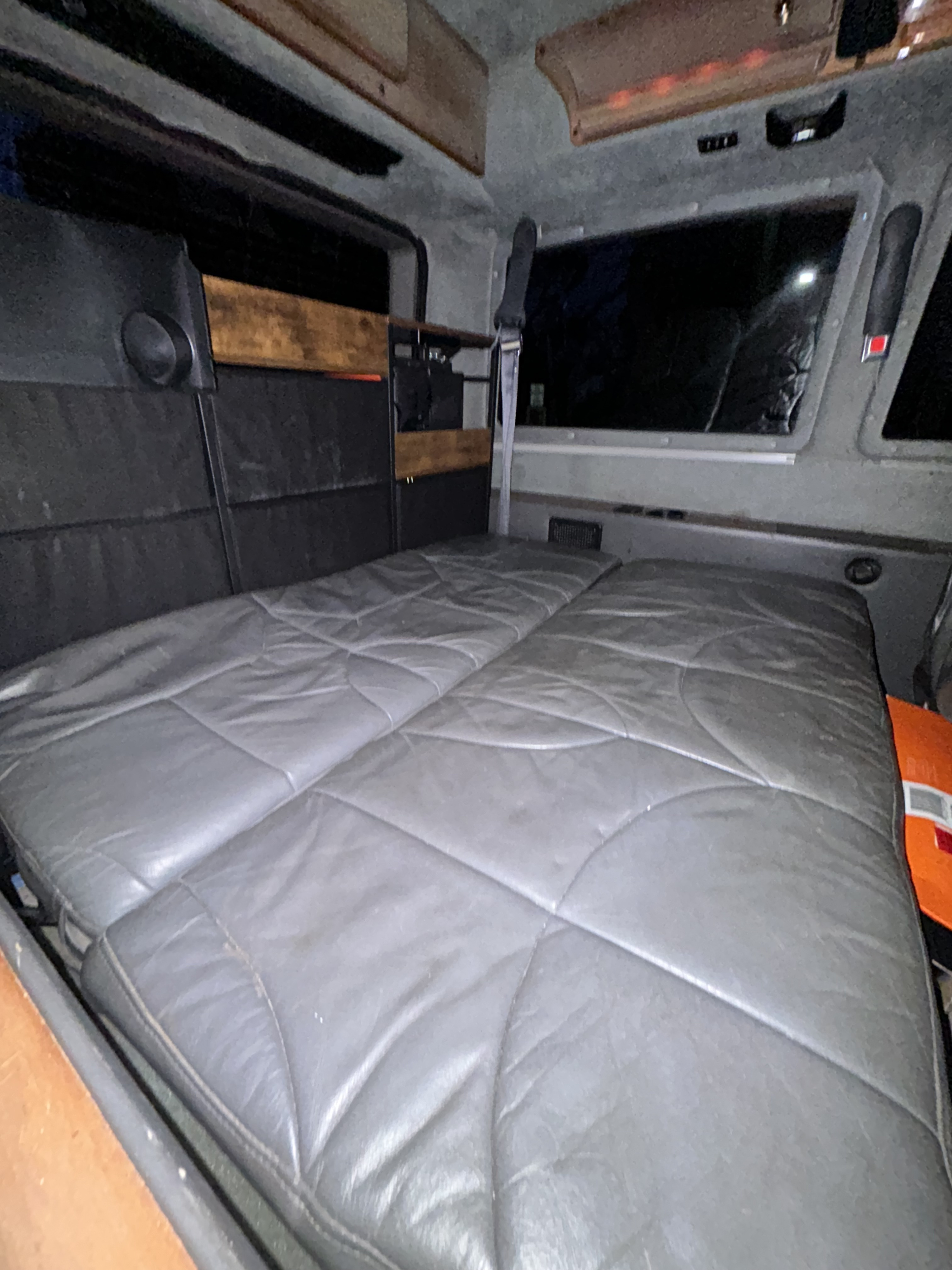 RV rental: Interior of a camper van with a spacious gray quilted bed, dark upholstery, and window.. Chevrolet Astro Van 2000