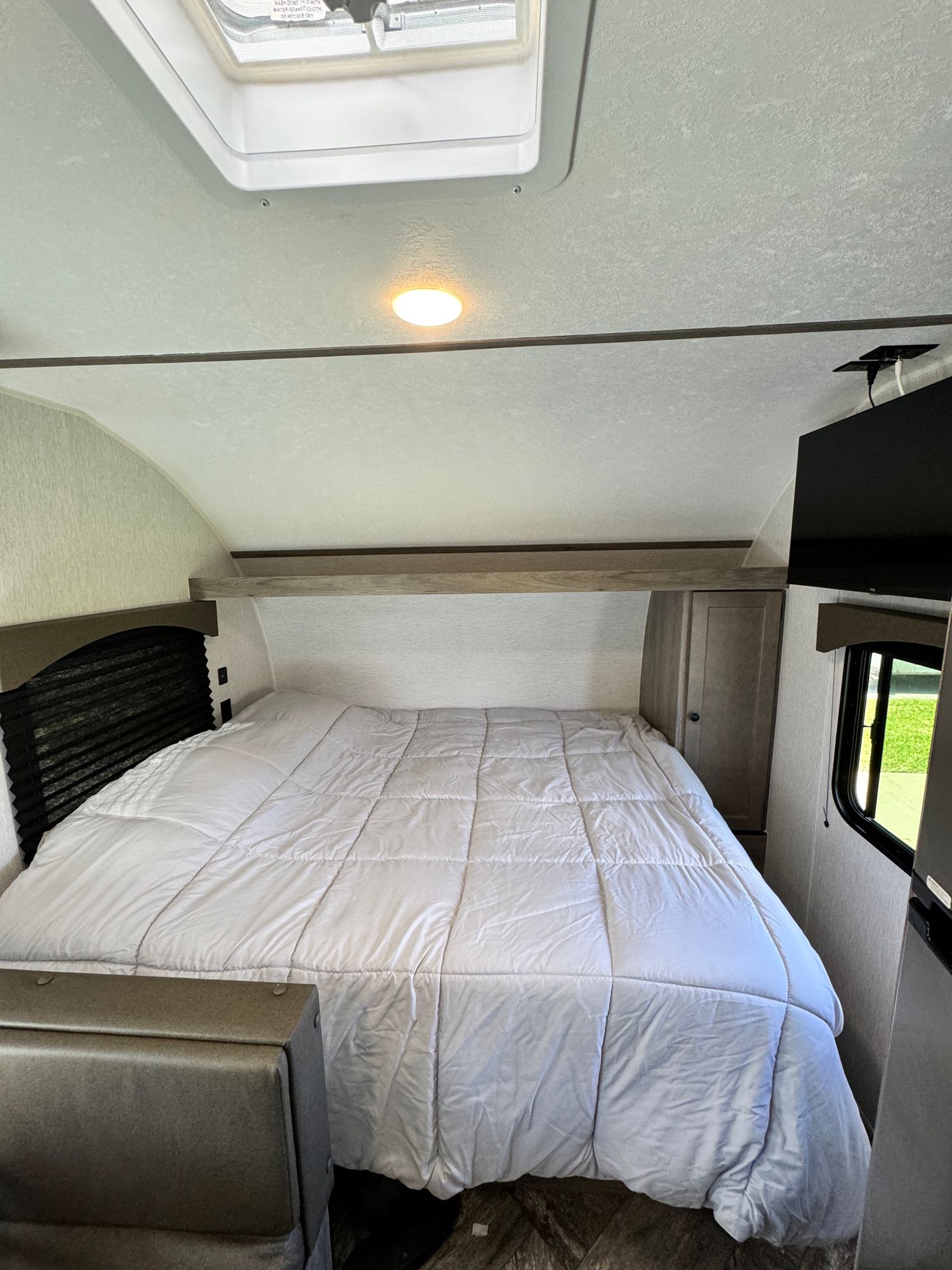Comfortable sleeping area inside an RV rental, featuring a queen bed, skylight, and TV for your travels.. Sunset Park RV Sun Lite LTD 2024