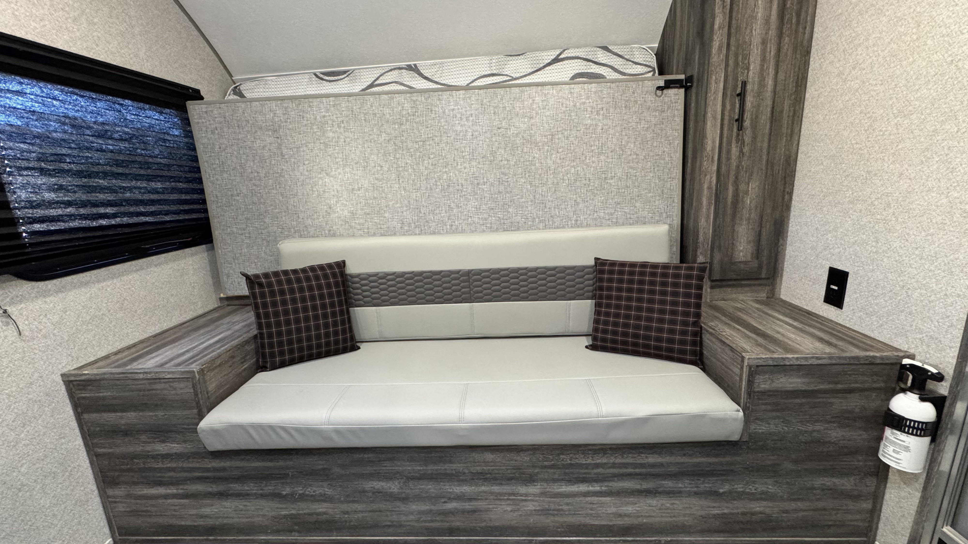 Cozy RV rental interior featuring convertible seating, overhead bed, window blinds, storage, and a fire extinguisher.. Forest River Salem FSX 2020