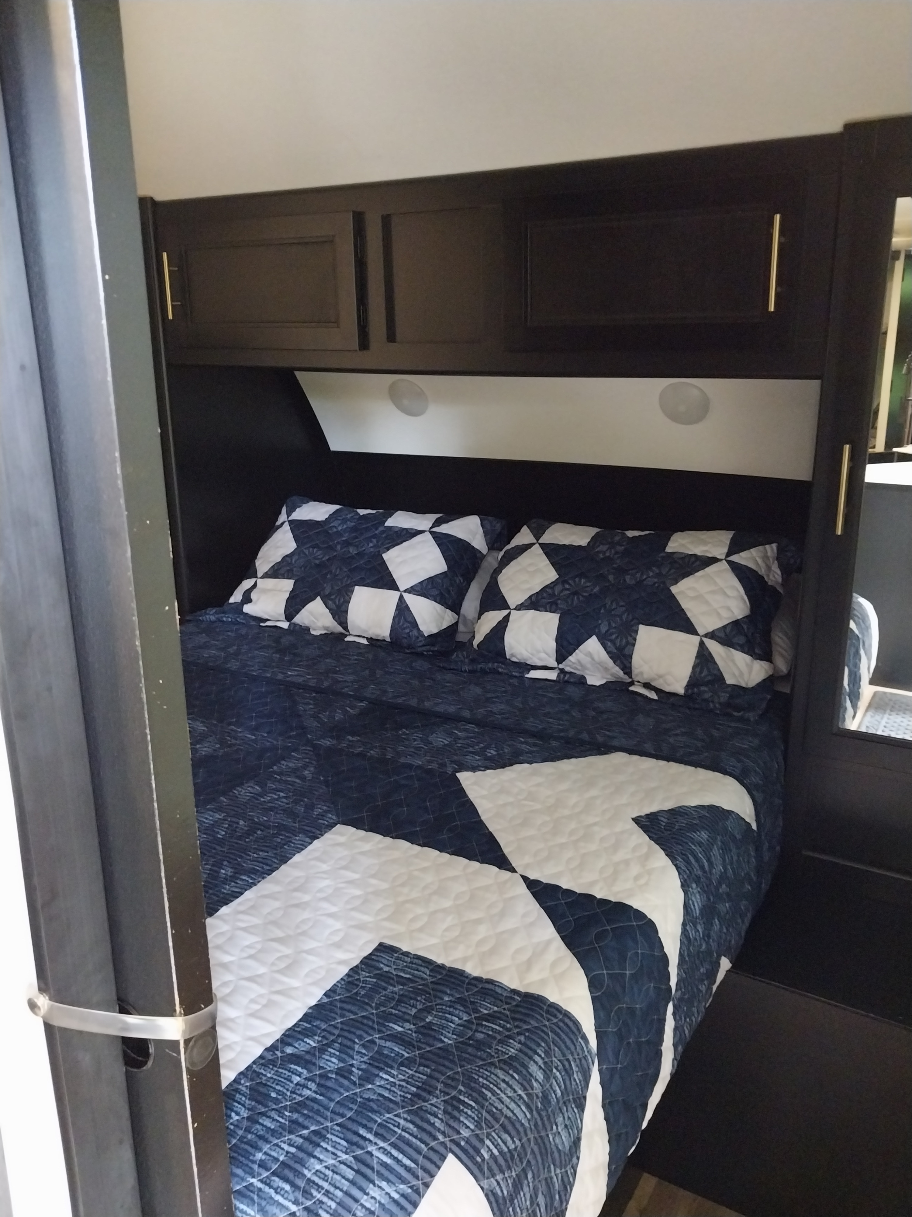 Cozy RV rental bedroom with patterned blue and white bedding, overhead storage, and integrated lighting for comfortable stays.. Forest River Cherokee Grey Wolf Black Label 2021