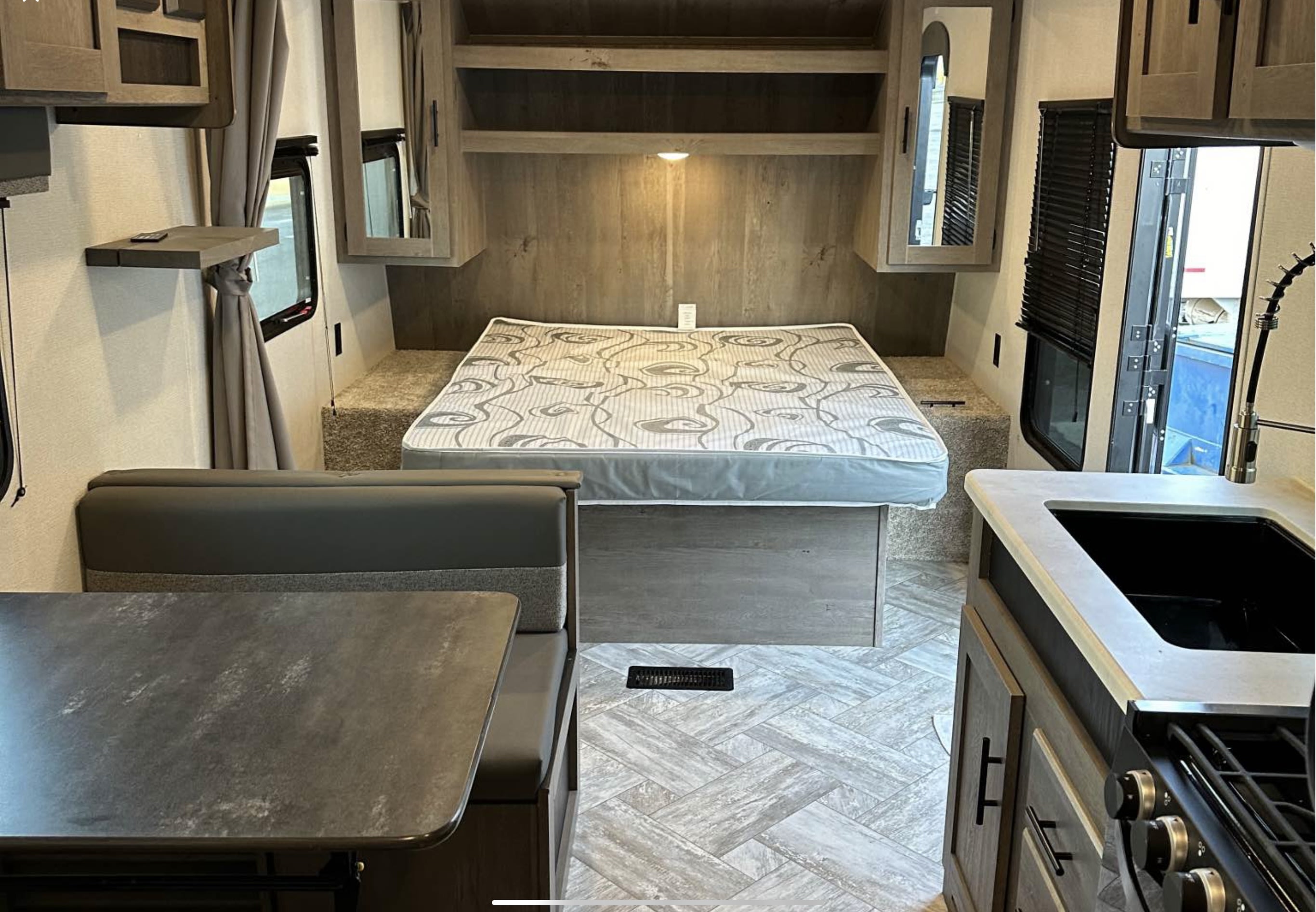 Spacious RV rental interior with bedroom, dinette, and kitchen. Light wood tones and modern design visible.. Keystone springdale 220 2021