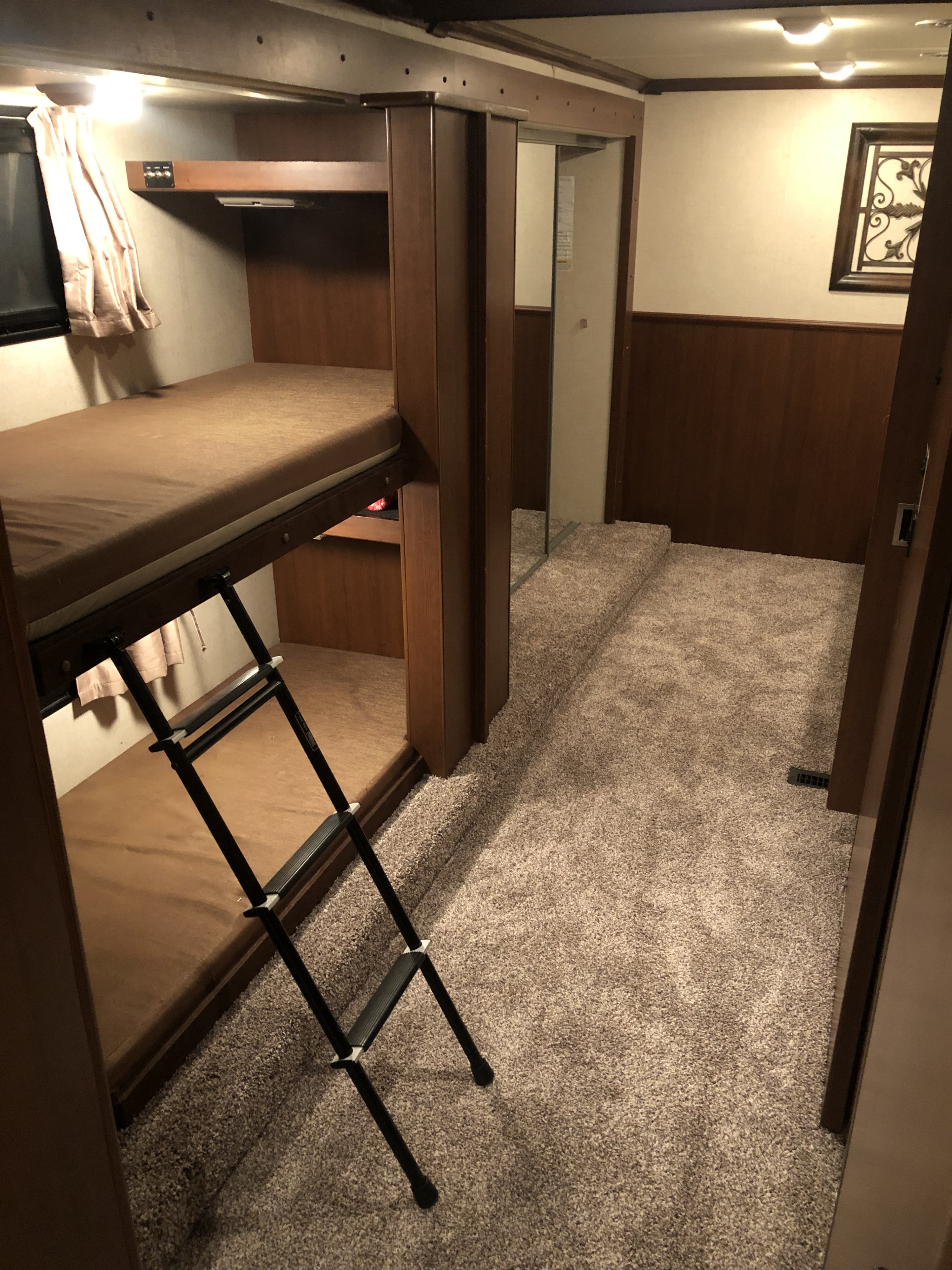 RV rental with built-in bunk beds and a ladder for access. Features a carpeted floor, wood paneling, and interior lighting.. Fleetwood Bounder 34B 2011
