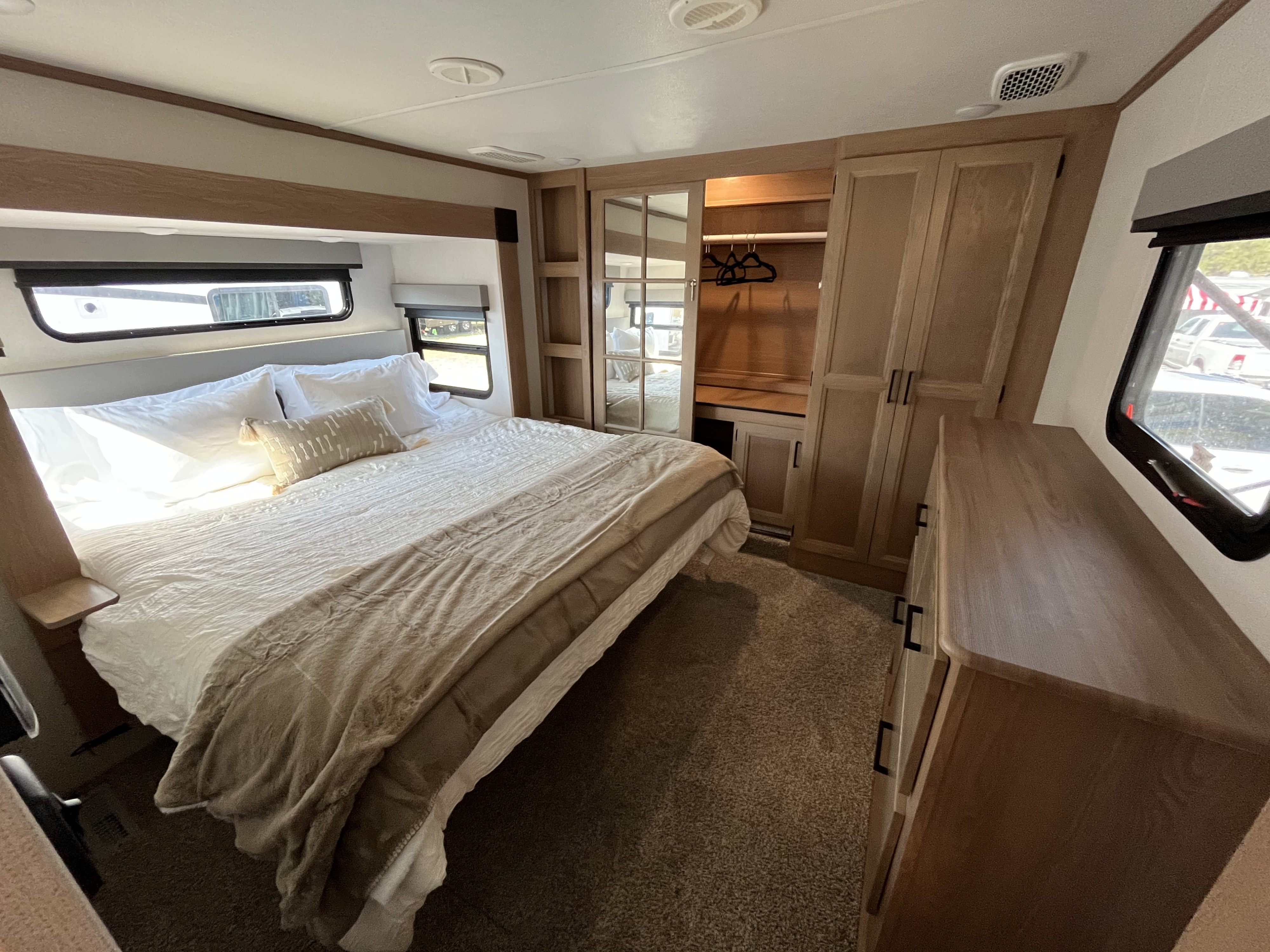 Cozy RV rental bedroom featuring a comfortable bed, mirrored closet, and dresser, offering a spacious interior.. Prime Time Sanibel  Wide Body 3102RSWB 2022